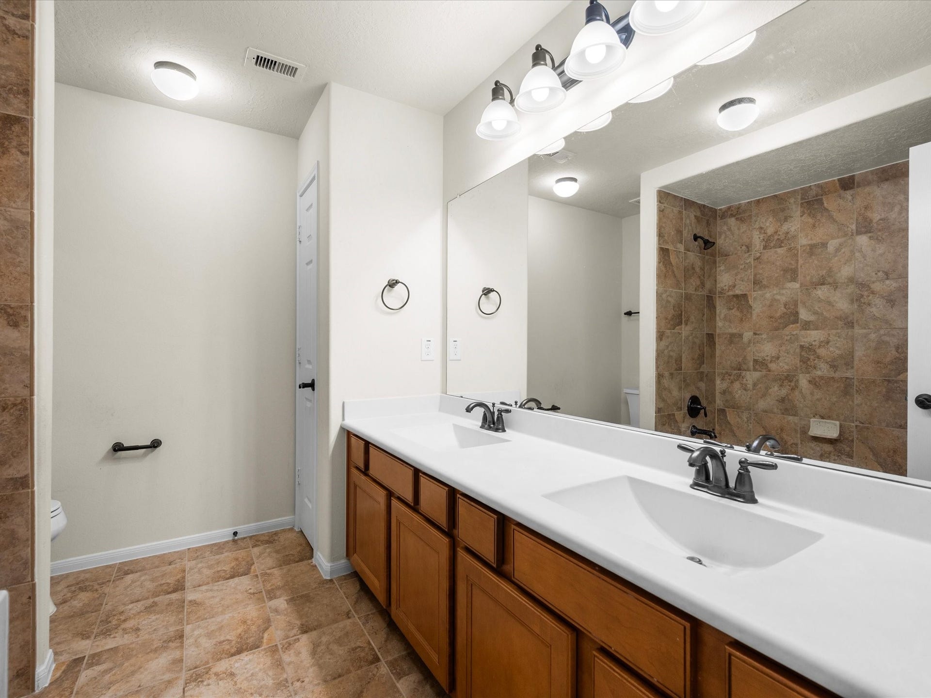 10458 Waterstone Estates Court, Tomball, TX 77375 One of three upstairs full bathrooms, this spacious bath features dual sinks and a tub-shower combination, offering convenience for daily routines and visiting guests.