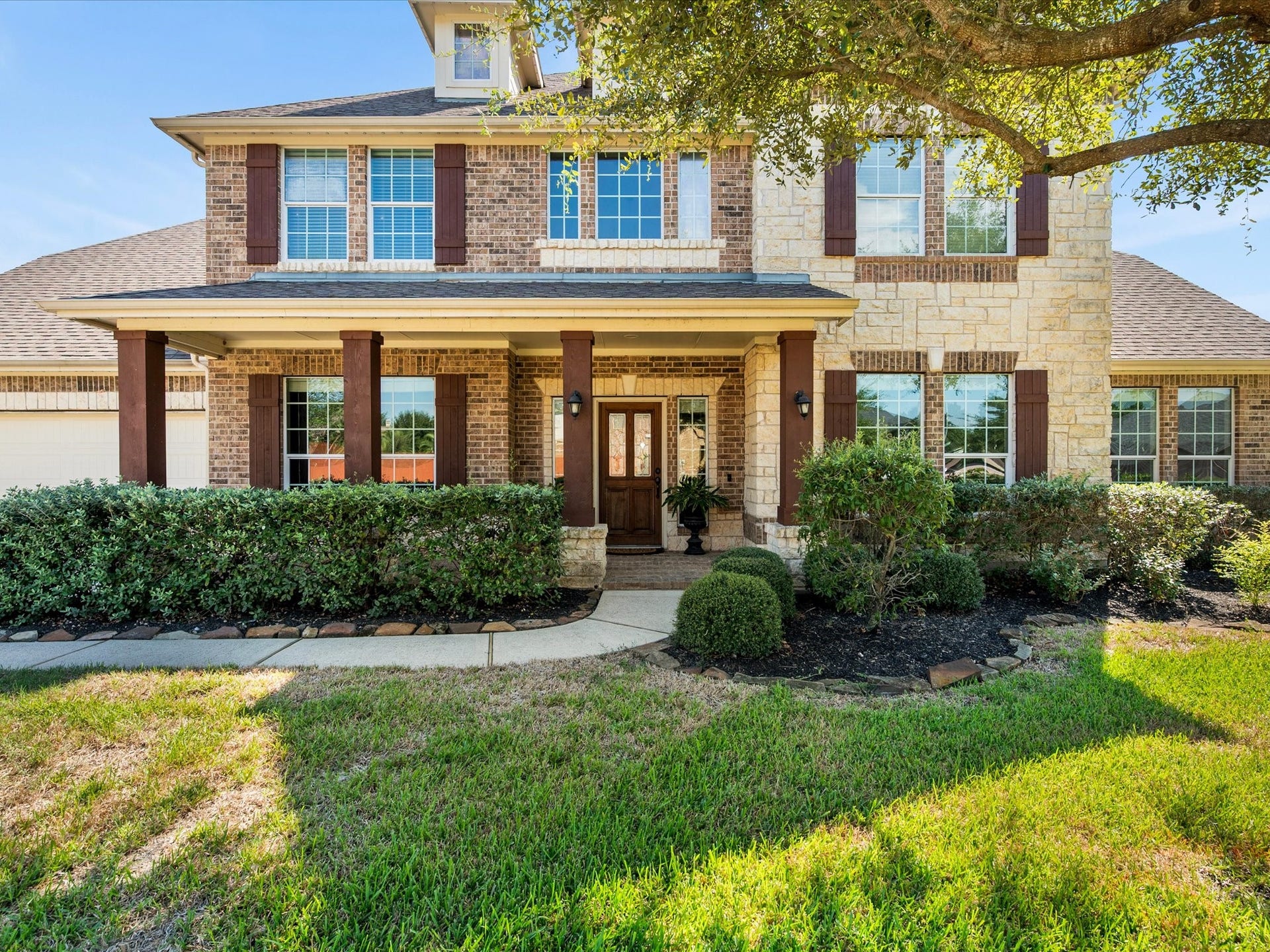 10458 Waterstone Estates Court, Tomball, TX 77375 Lush landscaping frames the inviting front porch, creating a warm first impression and a lovely place to enjoy a quiet moment outdoors.
