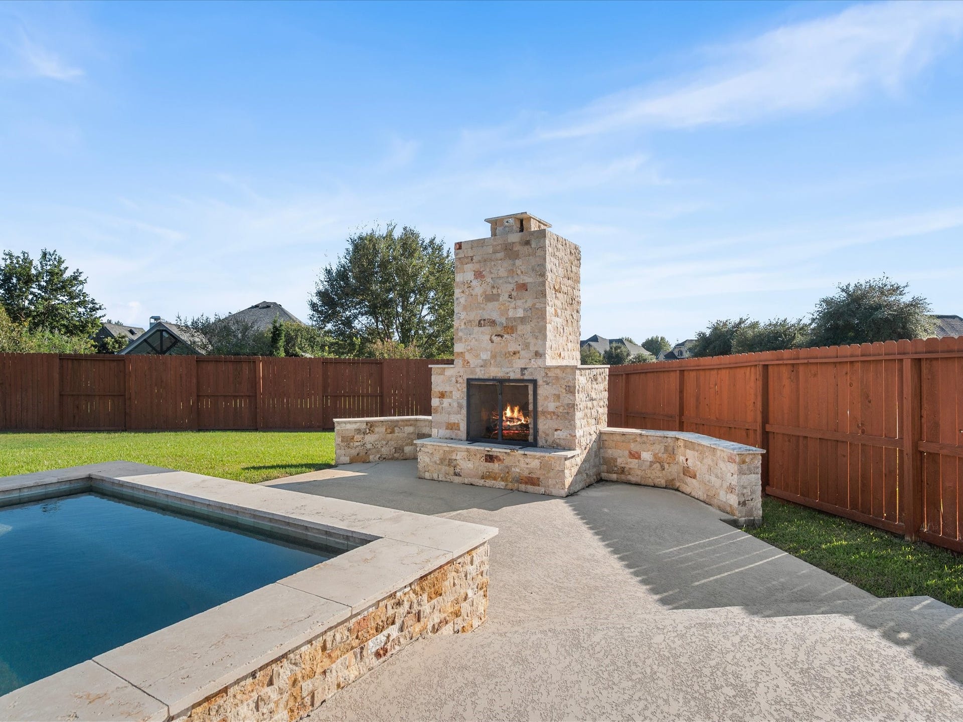 10458 Waterstone Estates Court, Tomball, TX 77375 Positioned beside the spa, the beautiful stone fireplace adds warmth and ambiance to the backyard, creating an inviting setting for relaxing outdoors long after sunset.