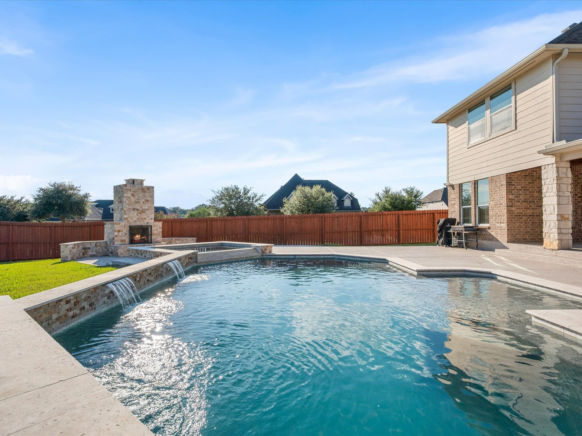 10458 Waterstone Estates Court, Tomball, TX 77375 A sparkling pool and spa, expansive covered patio, and outdoor fireplace create an exceptional setting for everything from quiet afternoons to lively gatherings.
