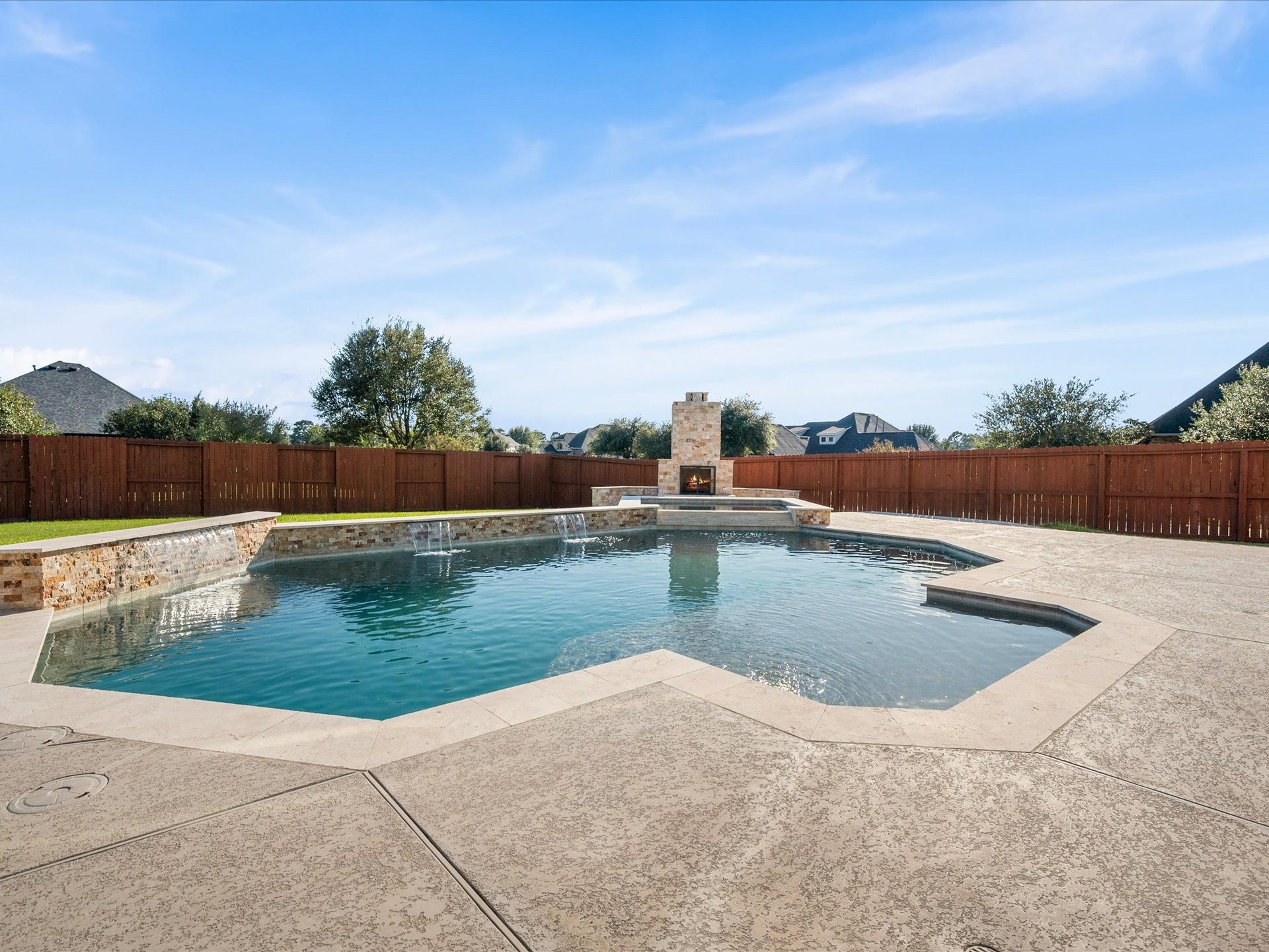 10458 Waterstone Estates Court, Tomball, TX 77375 Waterfall features bring movement and visual interest to the sparkling pool, complemented by generous patio space for lounging, gathering, and enjoying sunny afternoons.
