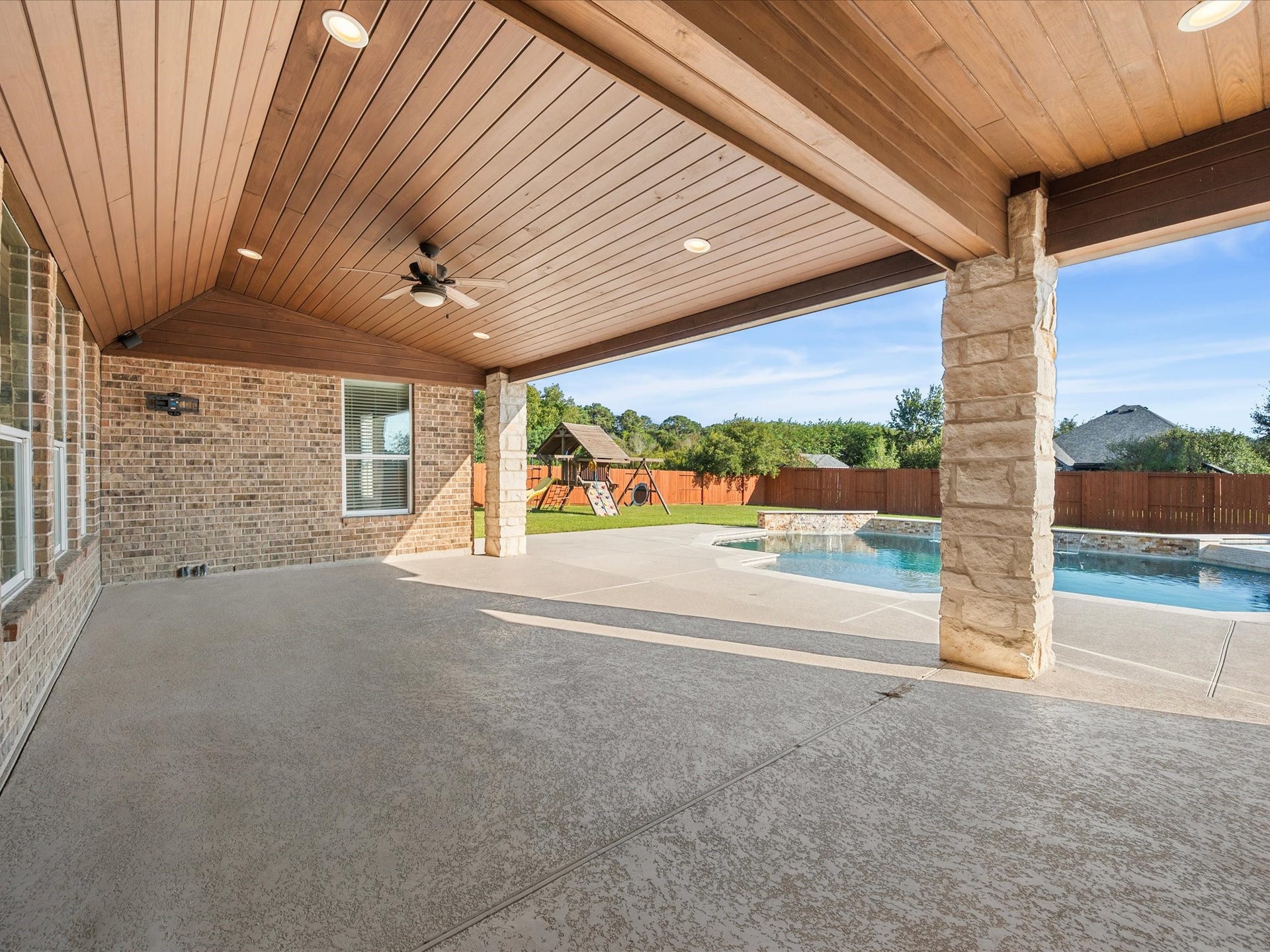 10458 Waterstone Estates Court, Tomball, TX 77375 The expansive covered patio overlooks the sprawling backyard, providing a shaded setting for outdoor dining, relaxed afternoons, and evenings spent enjoying the poolside surroundings.