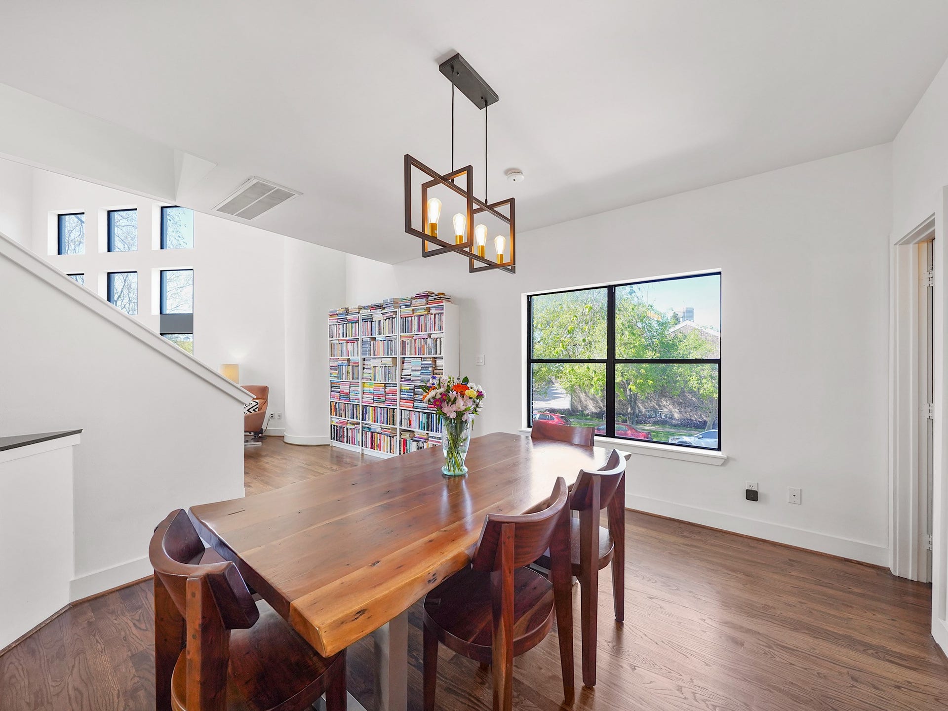 1231 Jackson Boulevard, Houston, TX 77006 This bright dining area features modern lighting, large windows for natural light, and a cozy reading nook with a bookshelf, creating a warm and inviting atmosphere.