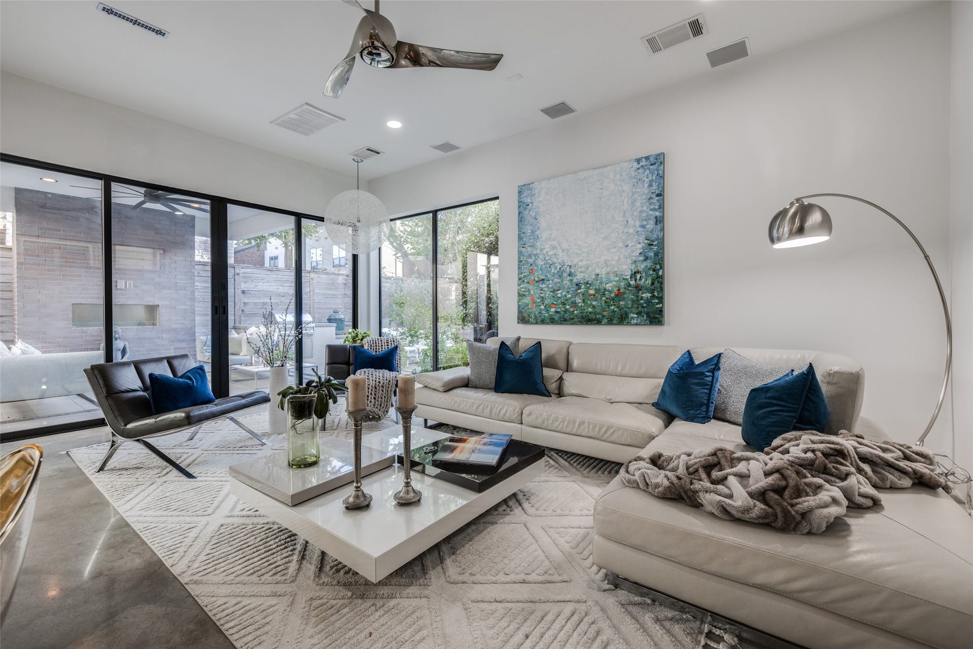 2014 Park Street, Houston, TX 77019 Spacious Living Room with walls of windows & sliding glass doors bringing the outdoors in, easy to maintain modern concrete floors, Minka Aire ceiling fan, LED recessed lights, in ceiling speakers