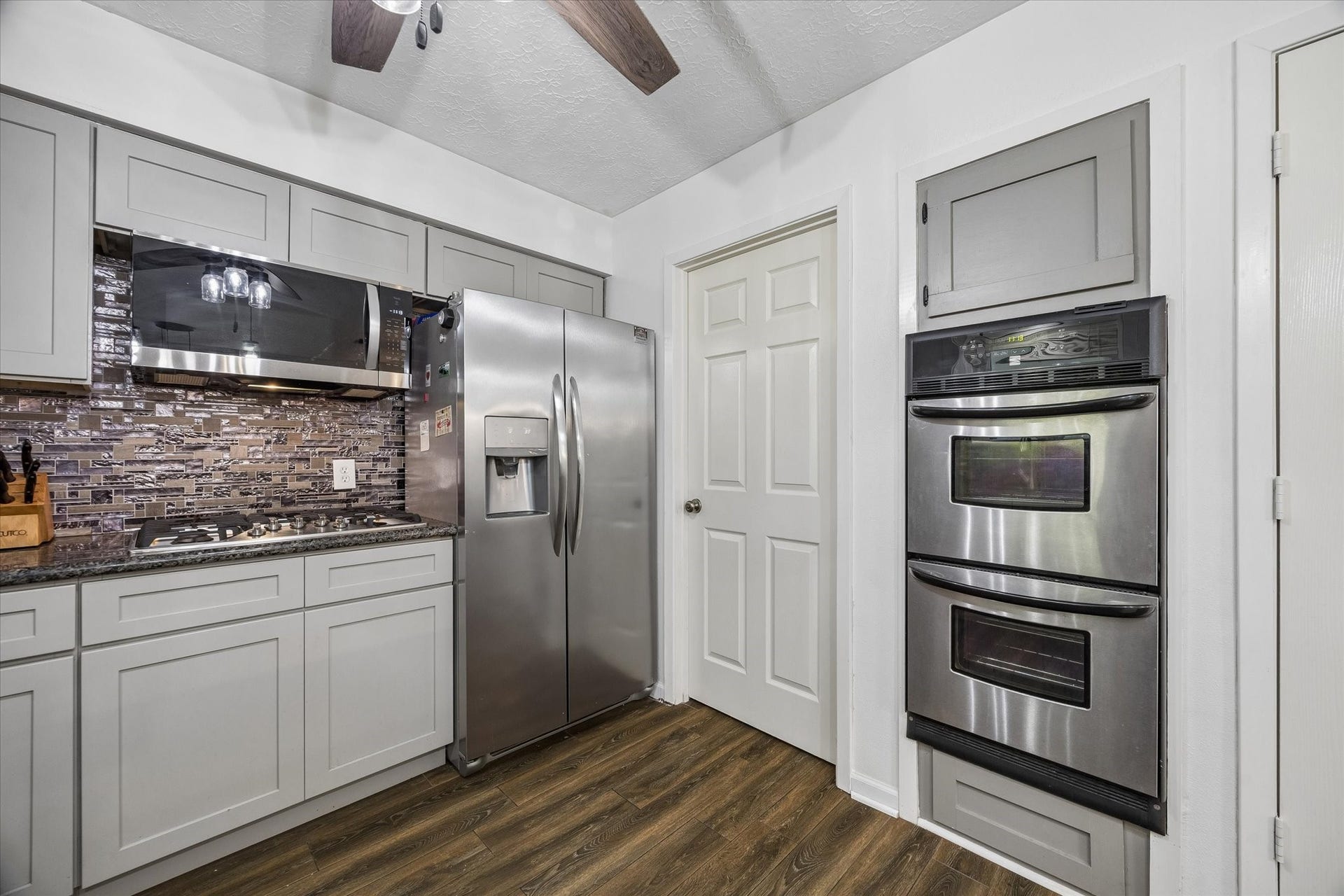 15726 Blackhawk Boulevard, Friendswood, TX 77546 Alternate view of the kitchen showing the double ovens, microwave, stainless frig, and door leading to utility room.