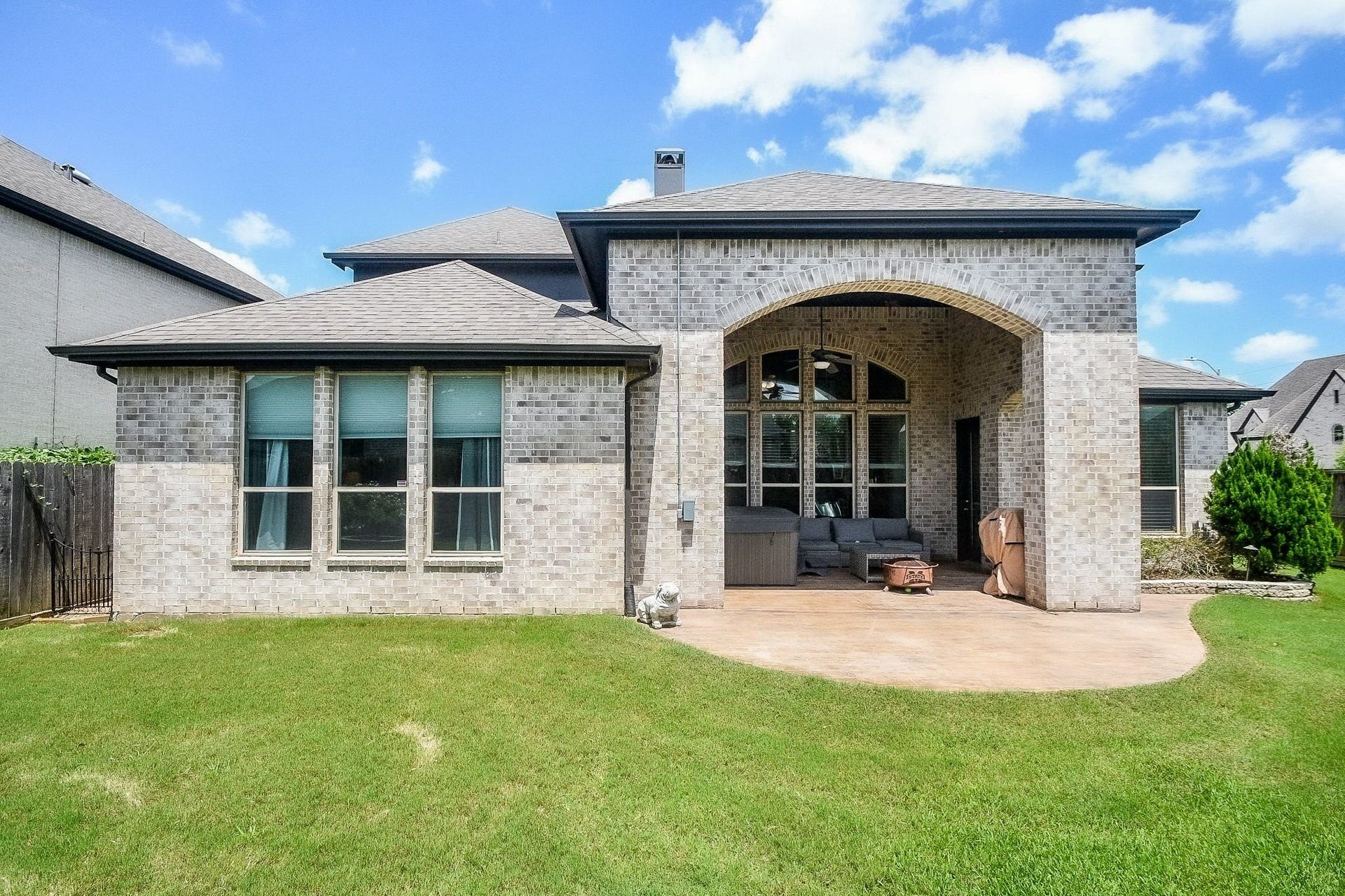 2703 Ripe Amber Cup Court, Richmond, TX 77406 Rear exterior view with covered patio, arched brick detail and backyard green space.