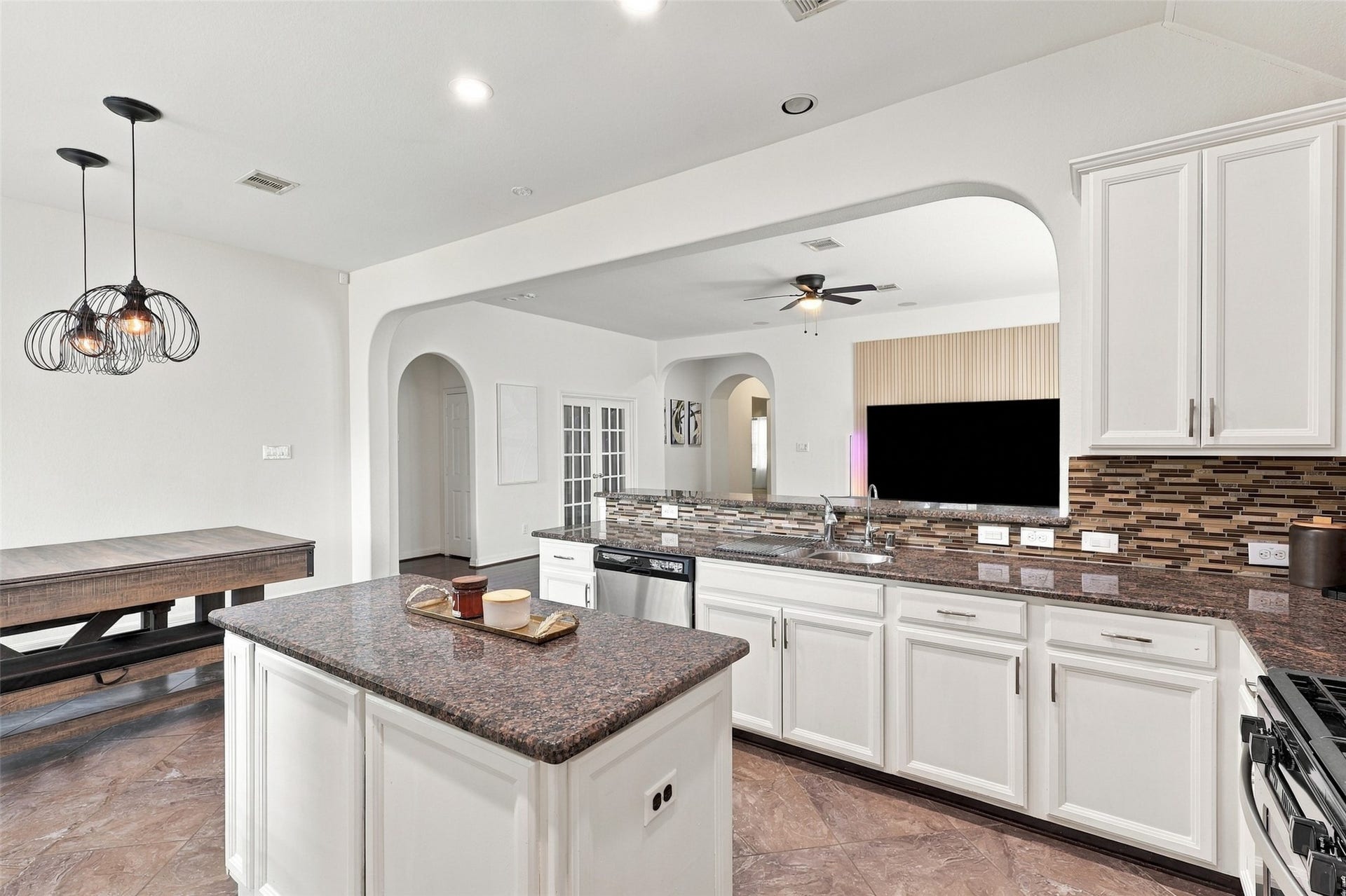 326 Lake Rim Drive, Rosenberg, TX 77469 Kitchen island and sink area overlooking the living room through a wide arched opening.