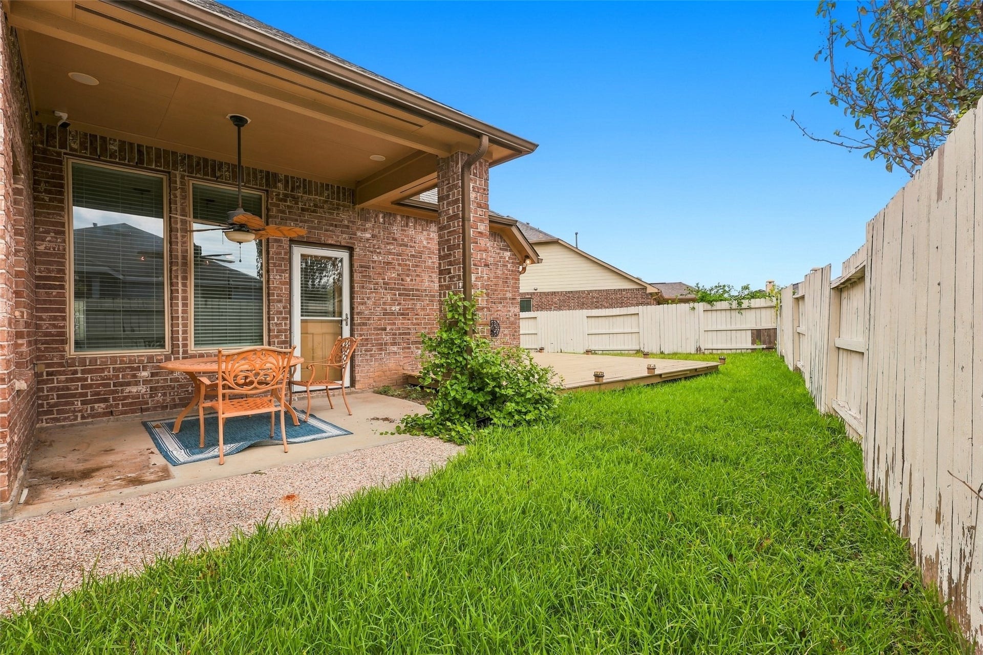 326 Lake Rim Drive, Rosenberg, TX 77469 Covered back patio with a ceiling fan, adjacent wood deck, and fenced lawn.