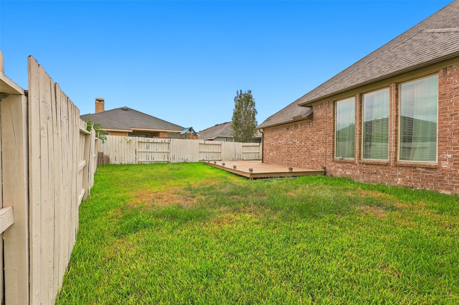326 Lake Rim Drive, Rosenberg, TX 77469 Additional backyard view highlighting the wood deck and lawn alongside the home.