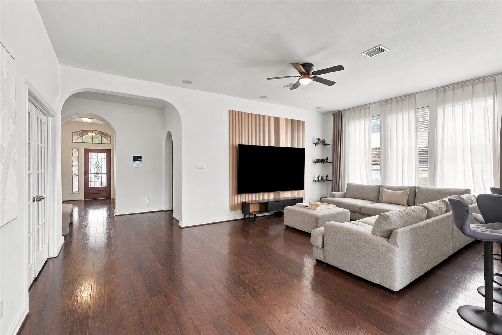 326 Lake Rim Drive, Rosenberg, TX 77469 Living area with wood flooring, a slatted accent wall, and views toward the front entry.