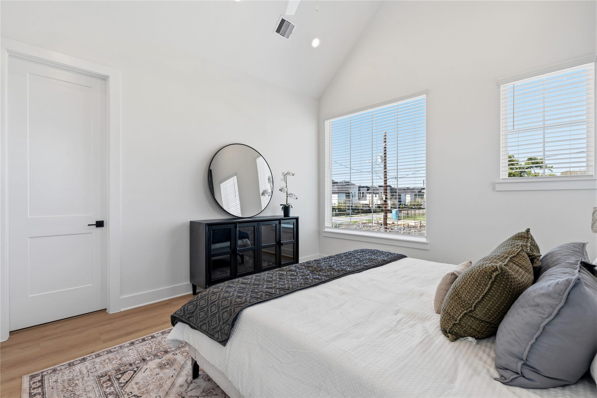 Large windows and high ceilings emphasize the room's airy, open atmosphere. The clean lines of the white doors and wide-plank flooring reinforce the home's contemporary aesthetic.