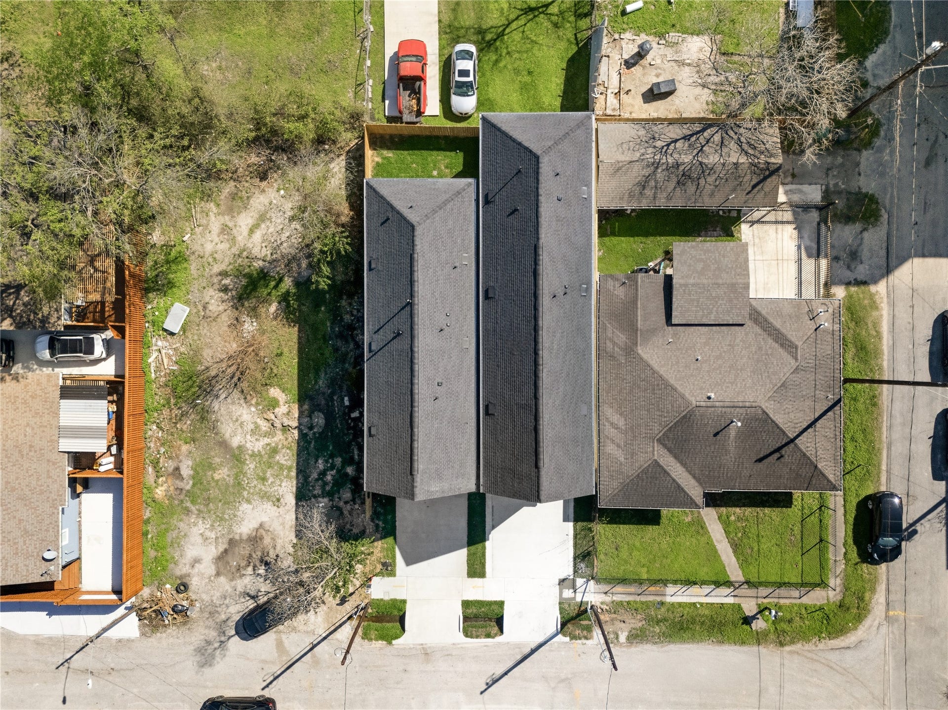 An aerial perspective reveals the sleek, dark-shingled gabled rooflines of the twin contemporary builds. The architecture maximizes the long, narrow footprint, integrating concrete driveways and private rear yards.