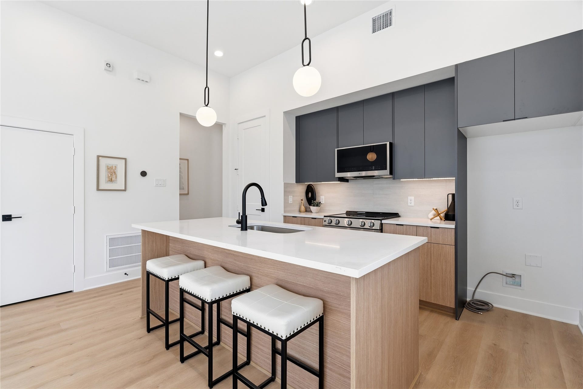 Contemporary duplex kitchen with quartz countertops, stainless appliances, and open sightlines to the living area.
