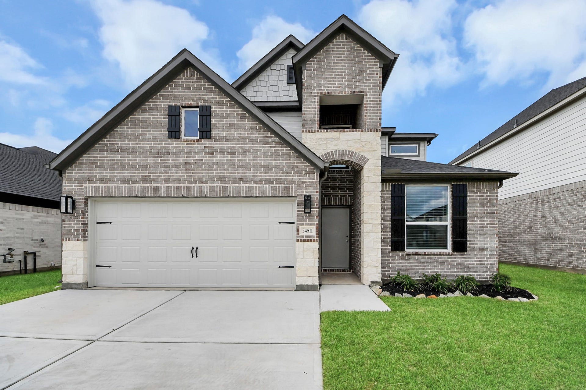 24511 Broad Park Ct, Spring, TX 77373 This home boasts lush green grass and meticulous landscaping. Its premium elevation showcases an exquisite blend of brick and stone features, complemented by modern coach lighting