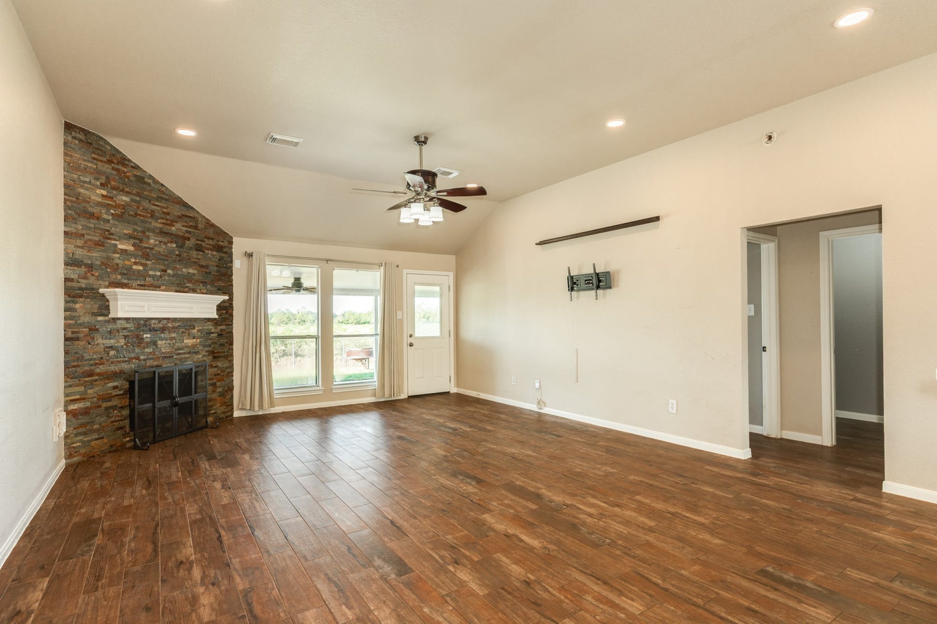 3425 Van Ness Drive, Alvin, TX 77511 Spacious living room with beautiful wood look tile flooring, a striking corner fireplace, and abundant natural light from large windows.