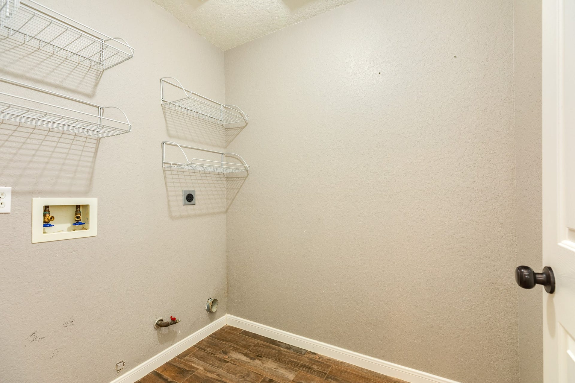 3425 Van Ness Drive, Alvin, TX 77511 Spacious laundry room with wall-mounted wire shelving, washer and dryer hookups, and durable flooring for convenience and functionality.