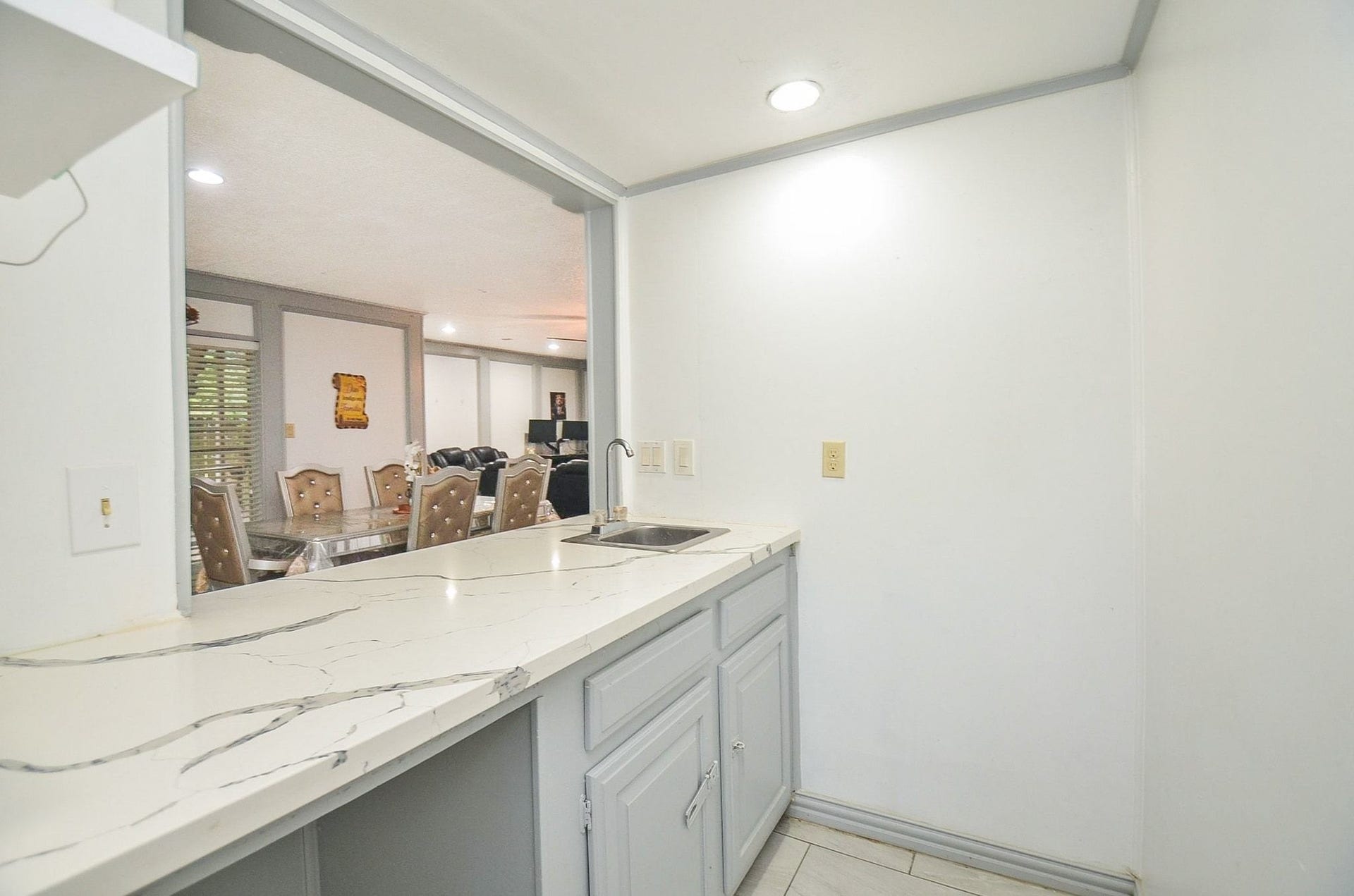 17821 S Cypress Villas Drive, Spring, TX 77379 Notice this tucked away dry bar with elegant marbled countertops, custom cabinetry, a prep sink, and a pass-through window overlooking the main living area.