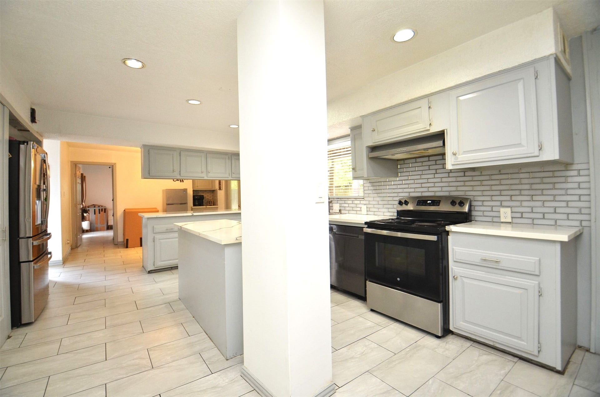 17821 S Cypress Villas Drive, Spring, TX 77379 Open kitchen with quartz island, gray cabinets, subway backsplash, stainless appliances, and tile floorsopens to dining/living.