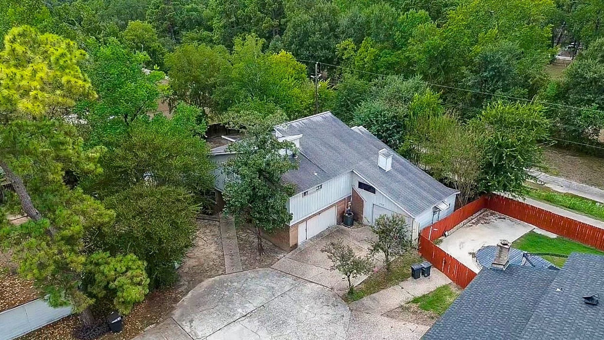 17821 S Cypress Villas Drive, Spring, TX 77379 Aerial perspective highlighting the spacious, mature-tree setting, long driveway, and multi-bay garage with fenced side yard.