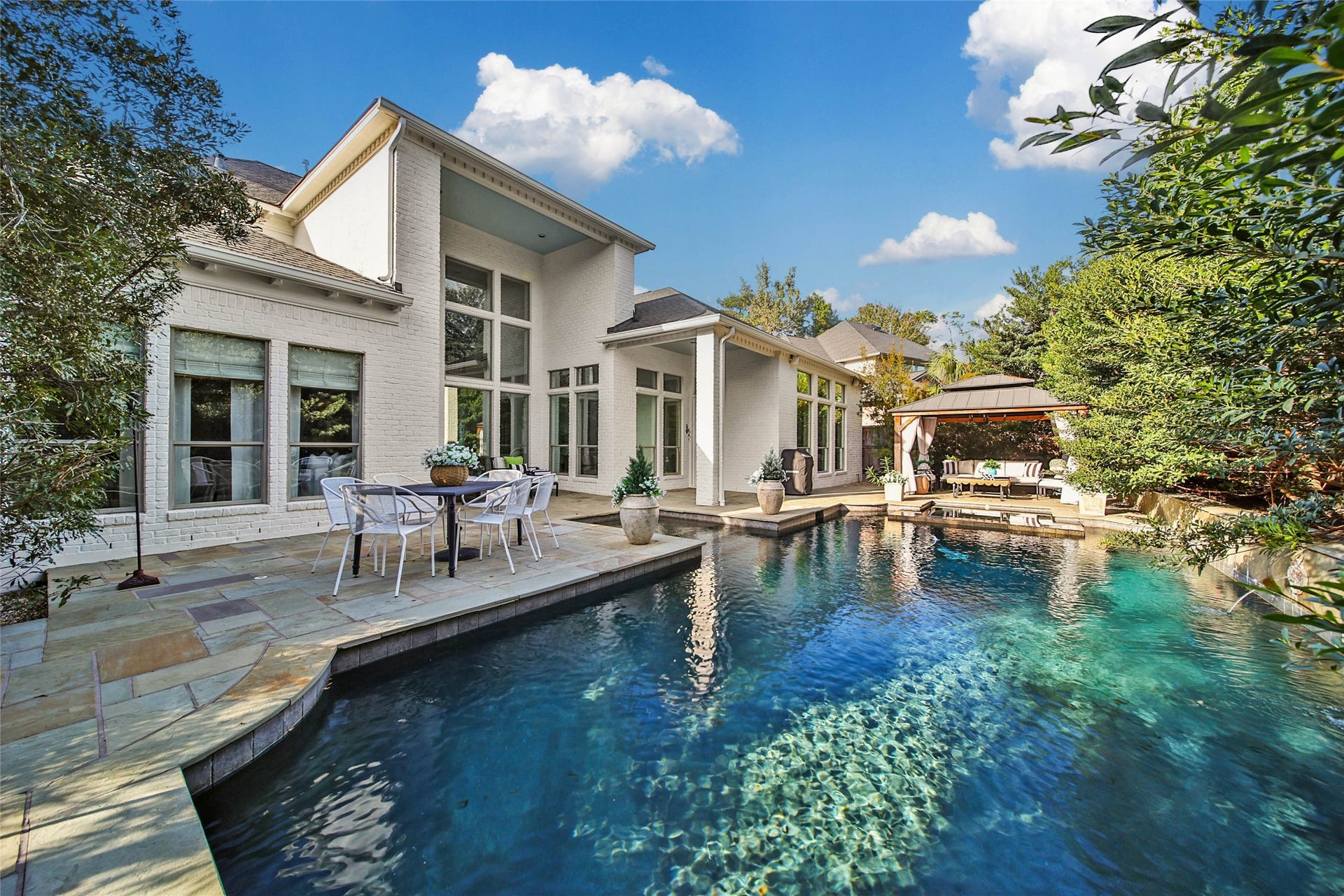 39 W Old Sterling Circle, The Woodlands, TX 77382 Backyard oasis featuring a sparkling pool, elegant patio area, and a cozy outdoor lounge, perfect for relaxation and entertaining.