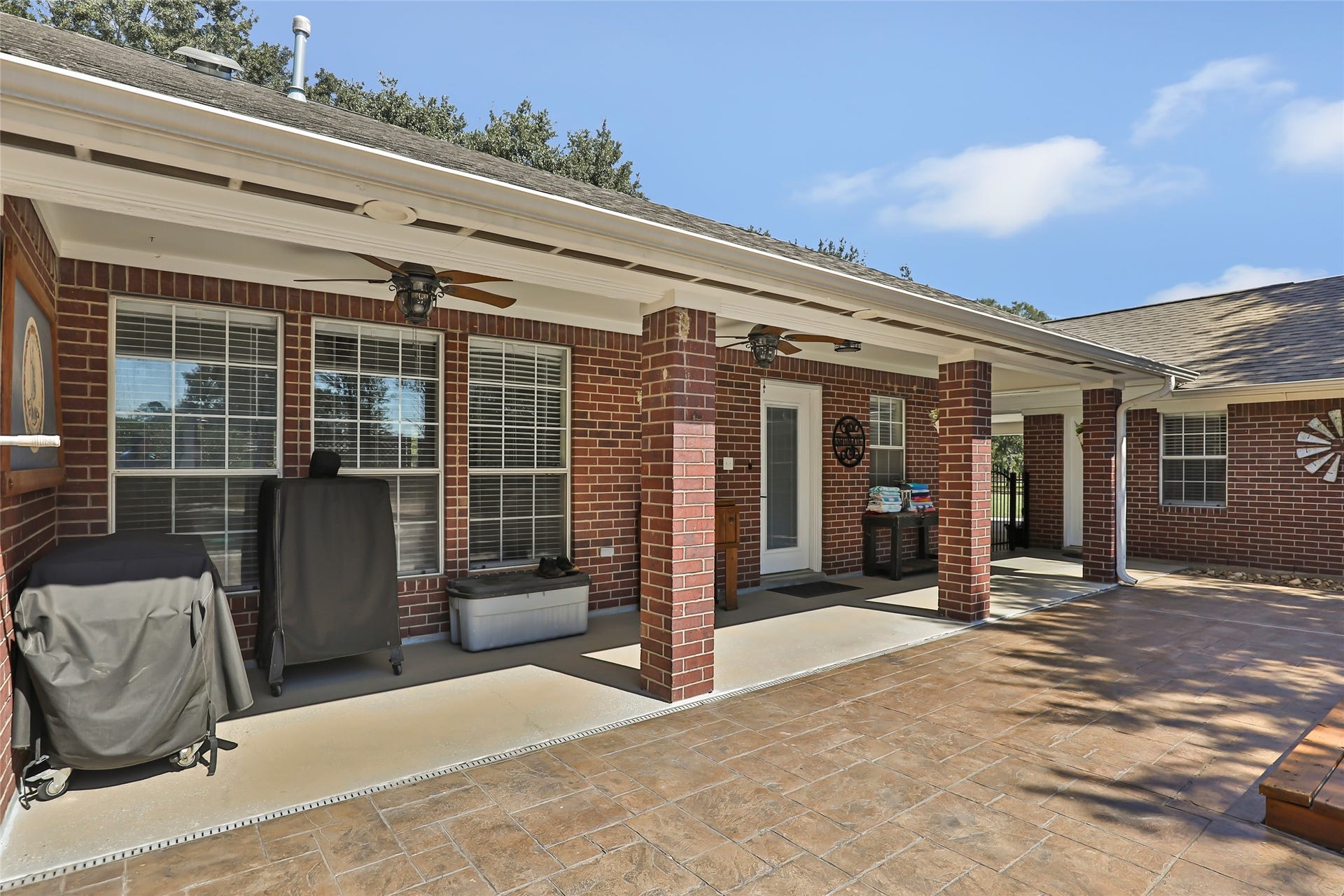 25107 Goodson Road, Splendora, TX 77372 Charming covered patio with brick exterior, ceiling fans, and ample space for outdoor entertaining.