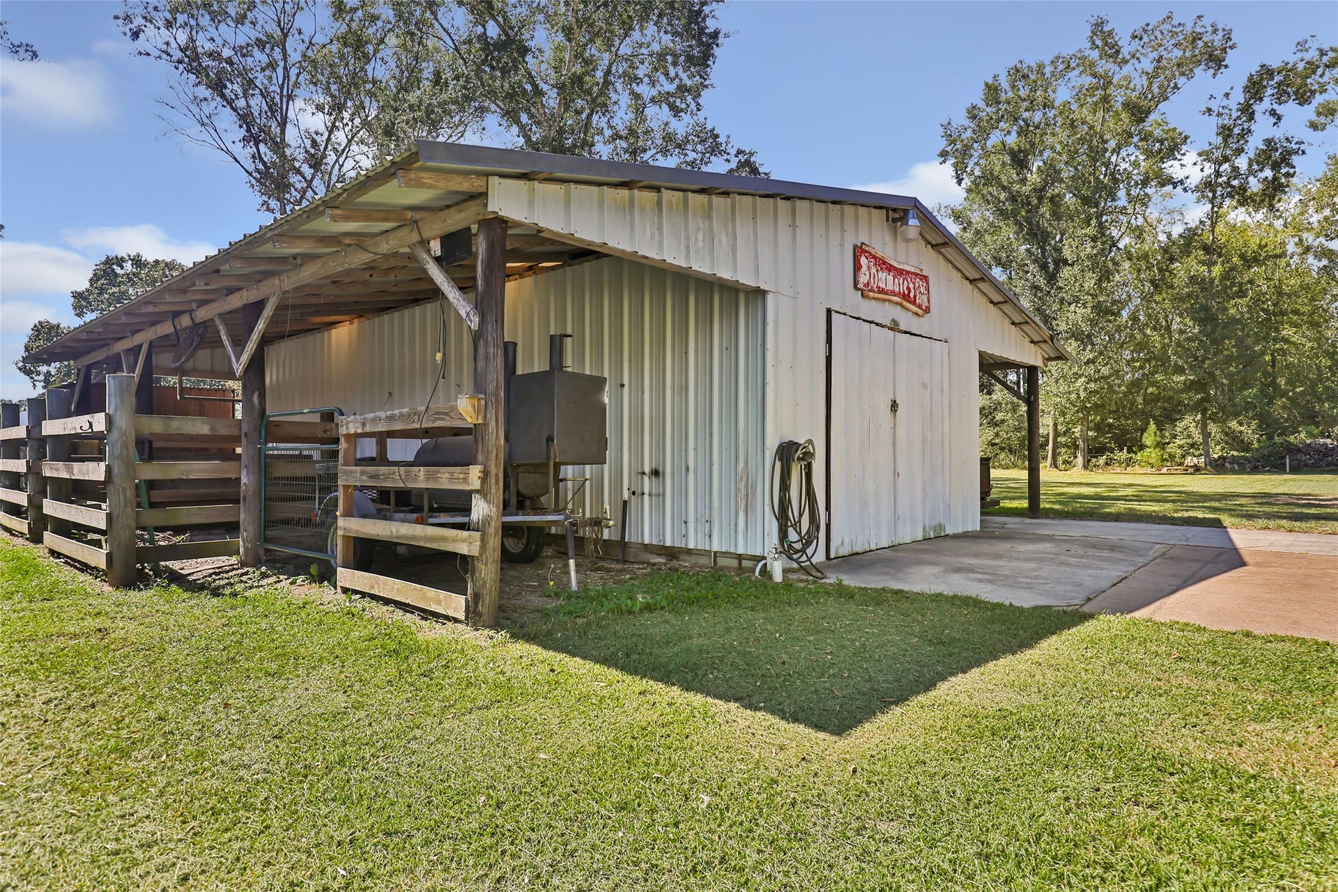 25107 Goodson Road, Splendora, TX 77372 Charming rustic barn with a covered area, perfect for storage or livestock, set amidst lush greenery.
