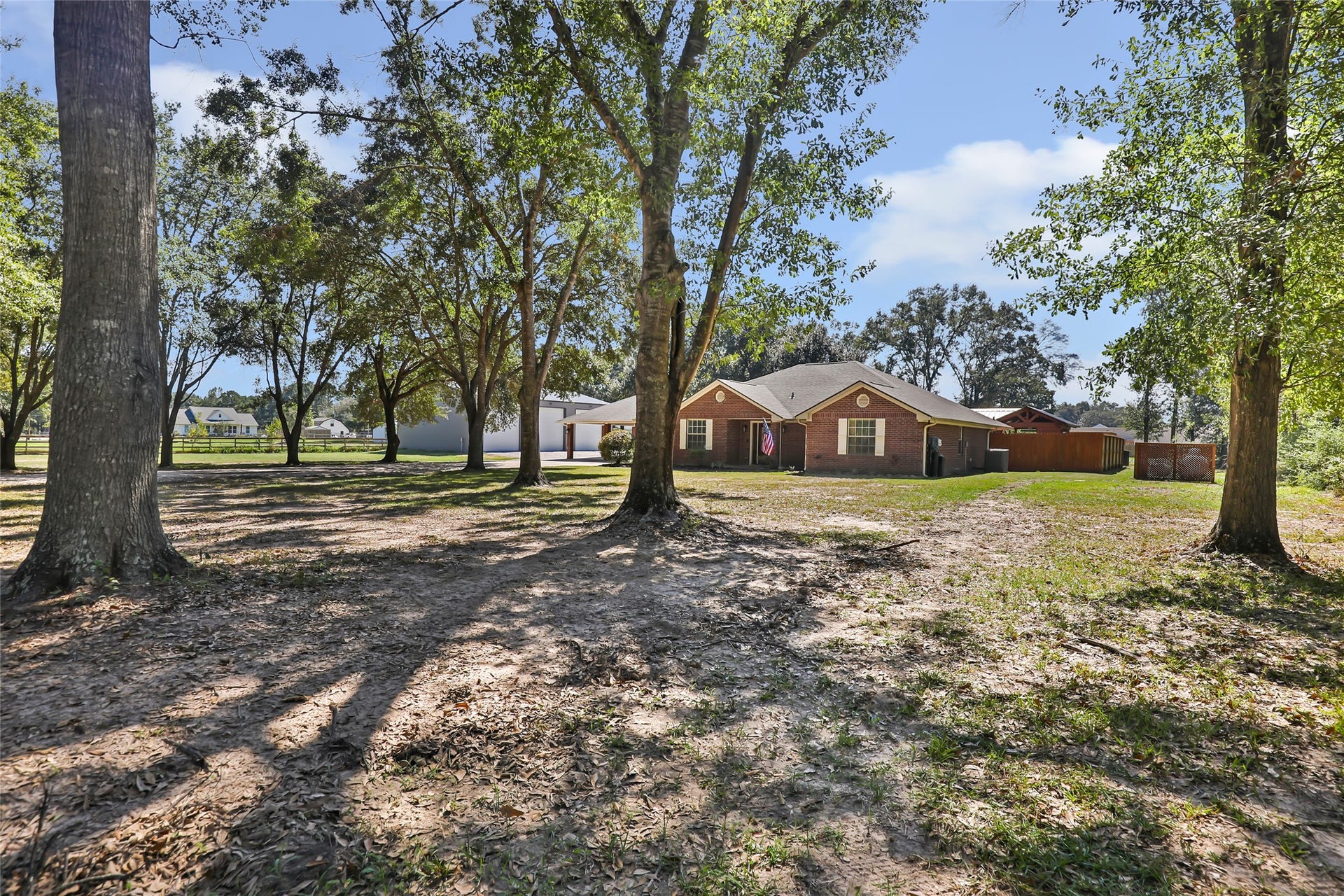 25107 Goodson Road, Splendora, TX 77372 Charming brick home nestled on a spacious, tree-lined lot offering ample shade and privacy, perfect for enjoying serene outdoor living.