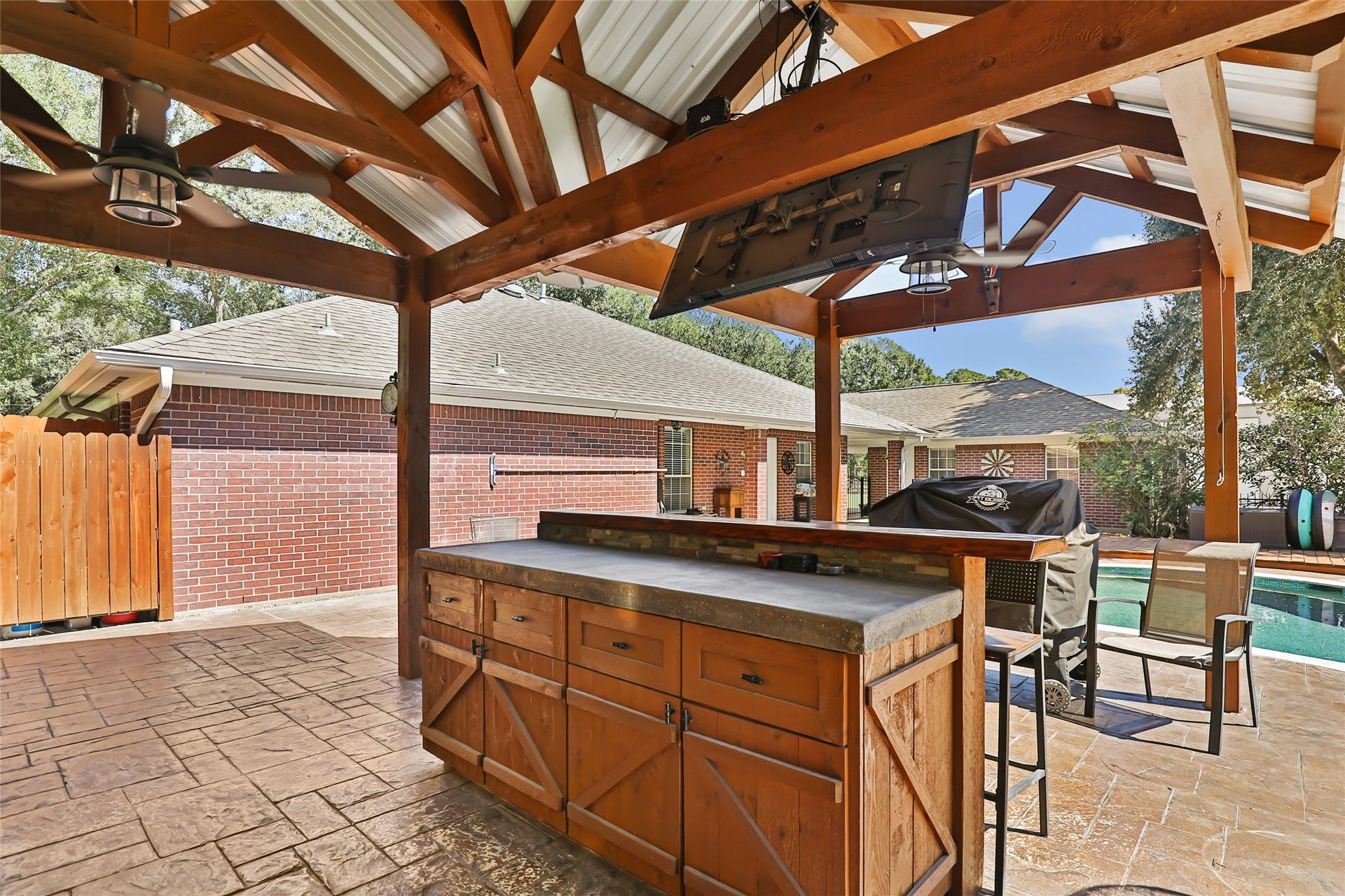 25107 Goodson Road, Splendora, TX 77372 Outdoor oasis featuring a covered patio with a built-in bar and grill area, perfect for entertaining by the pool.