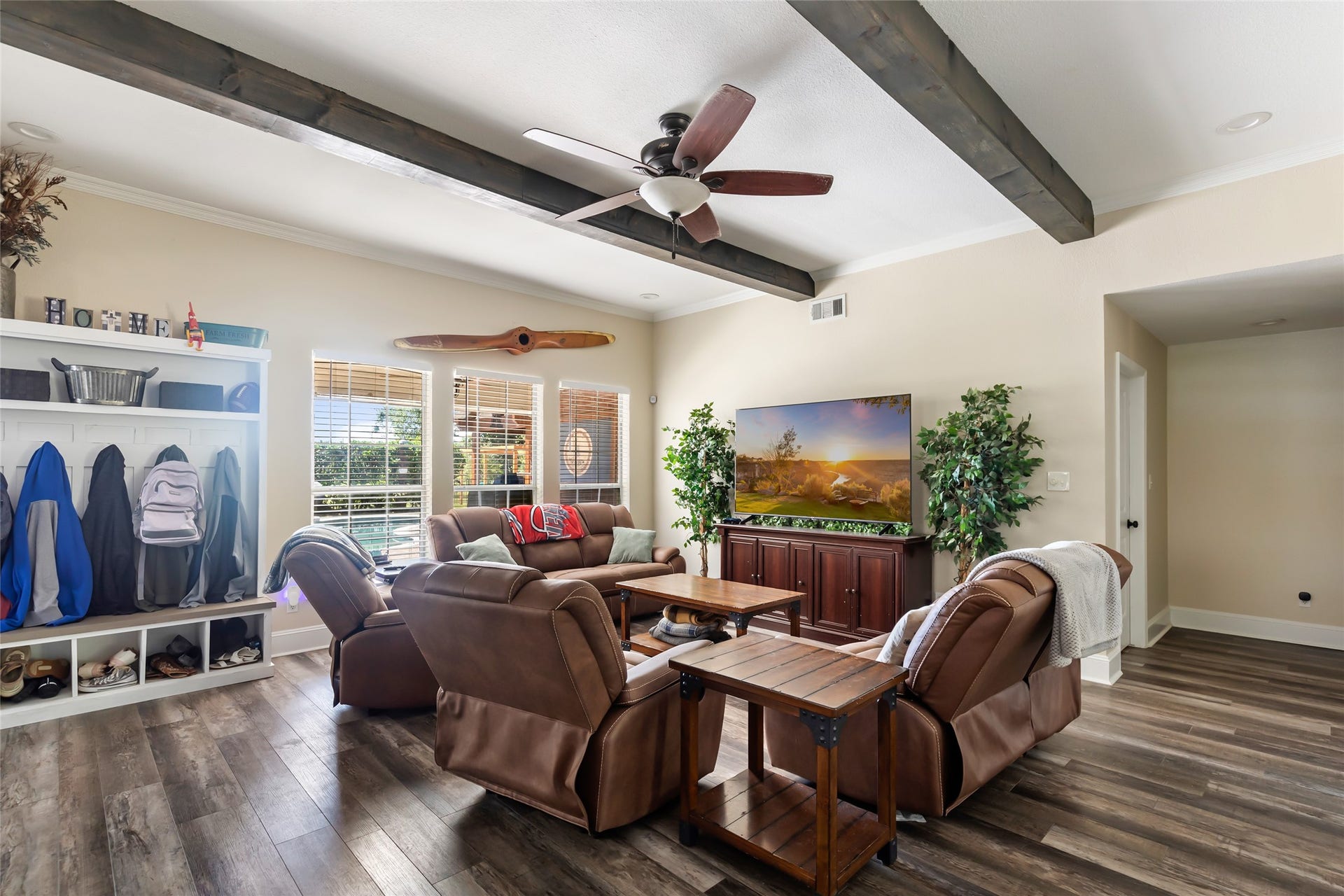 25107 Goodson Road, Splendora, TX 77372 Charming living room with exposed wood beams, cozy seating, large windows for natural light, and stylish shelving for storage.