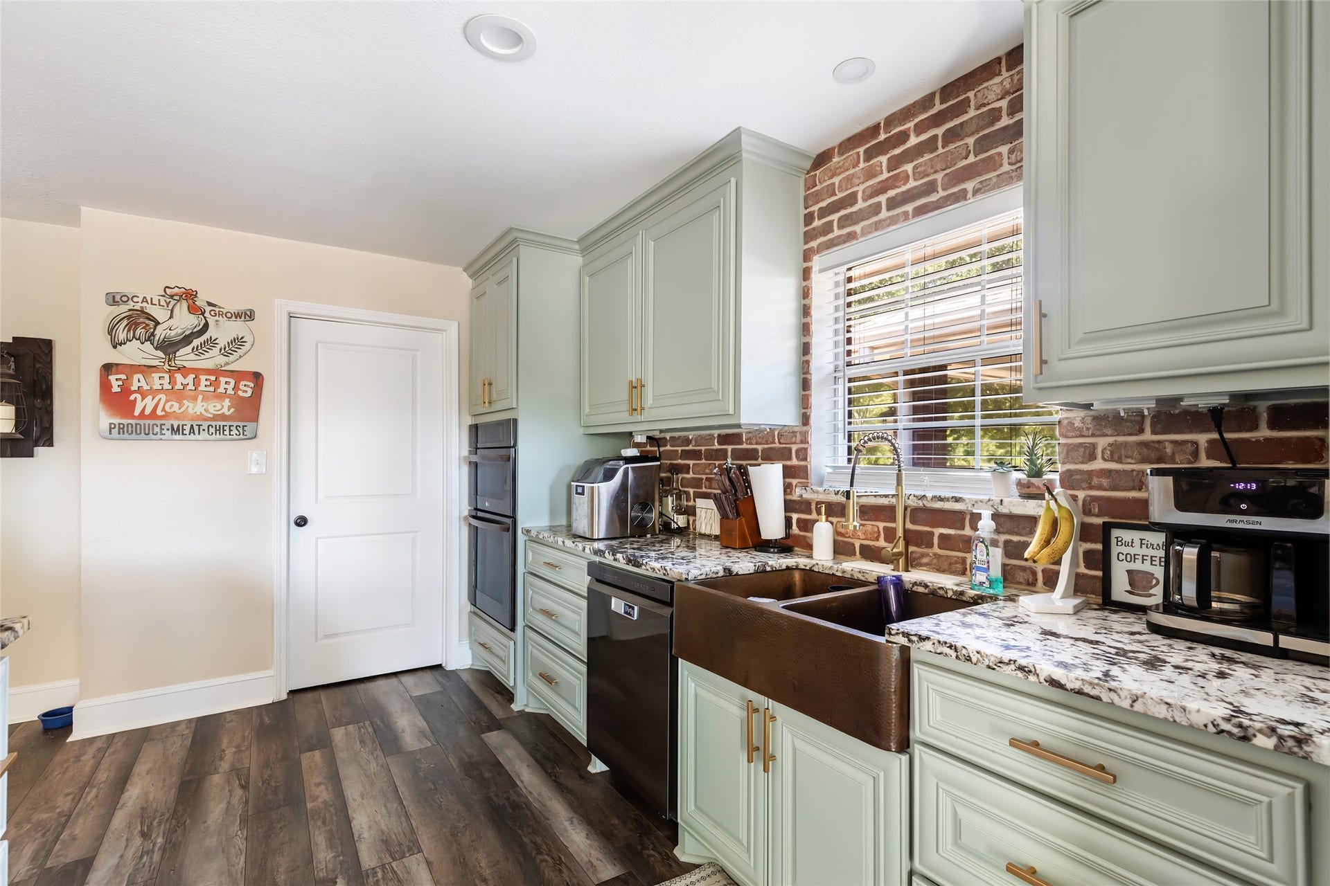 25107 Goodson Road, Splendora, TX 77372 Charming kitchen with rustic brick backsplash, light green cabinets, and granite countertops, featuring a farmhouse sink and modern appliances.