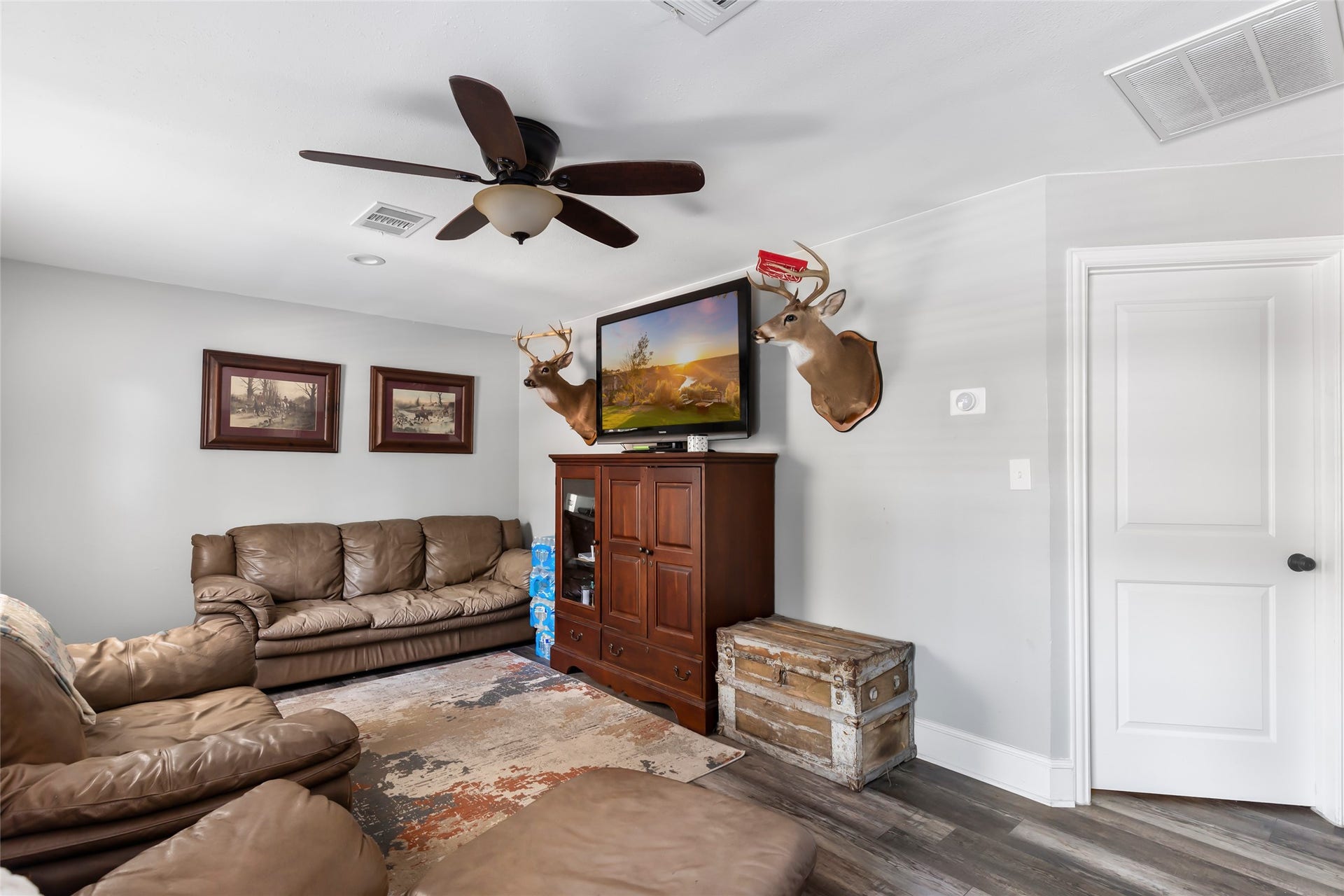 25107 Goodson Road, Splendora, TX 77372 Cozy living room featuring comfortable leather seating, a ceiling fan, and rustic decor, perfect for relaxation and entertainment.