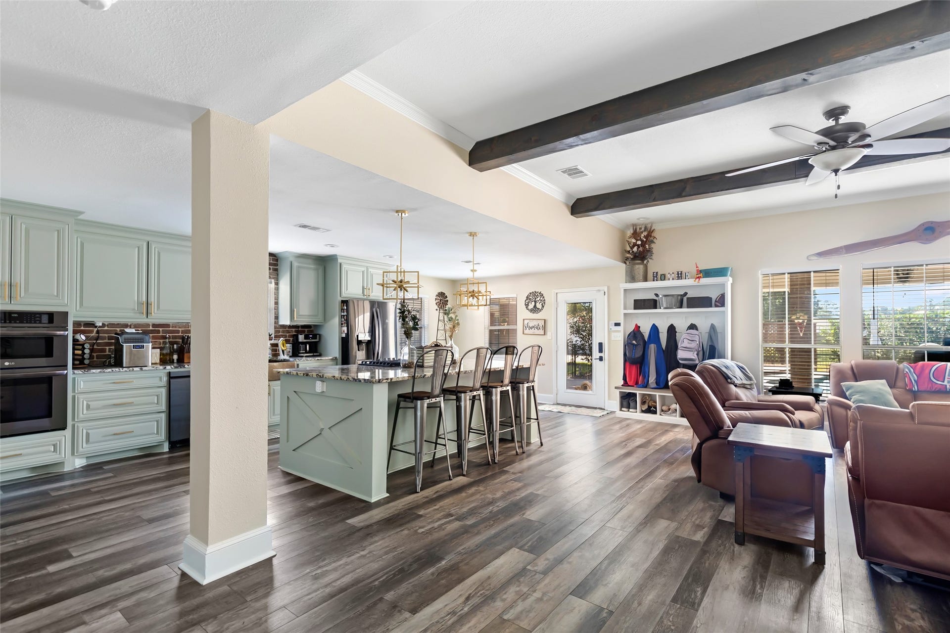 25107 Goodson Road, Splendora, TX 77372 Experience open-concept living with a spacious kitchen featuring mint cabinetry and a large island, seamlessly flowing into a cozy living area with exposed beams and abundant natural light.