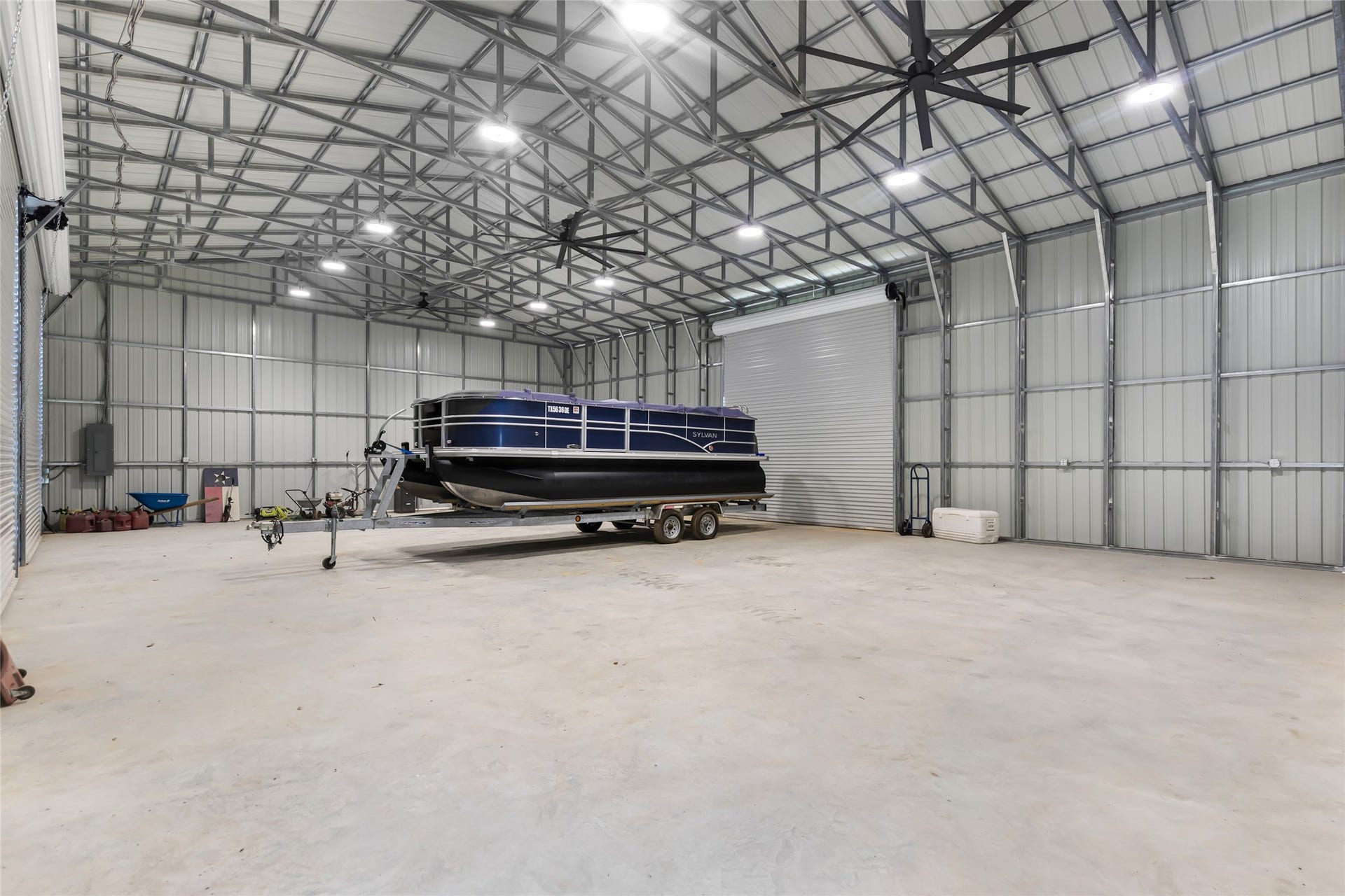 25107 Goodson Road, Splendora, TX 77372 Spacious and versatile metal outbuilding with high ceilings, perfect for boat storage or a workshop, featuring large roll-up doors for easy access.