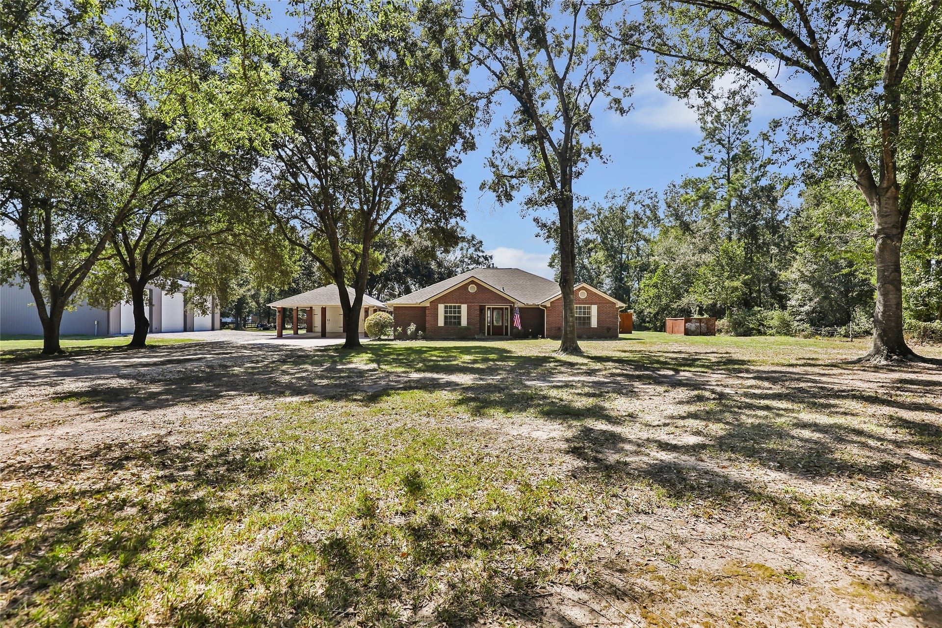 25107 Goodson Road, Splendora, TX 77372 Charming brick home nestled among mature trees, offering ample shade and a serene, private setting.