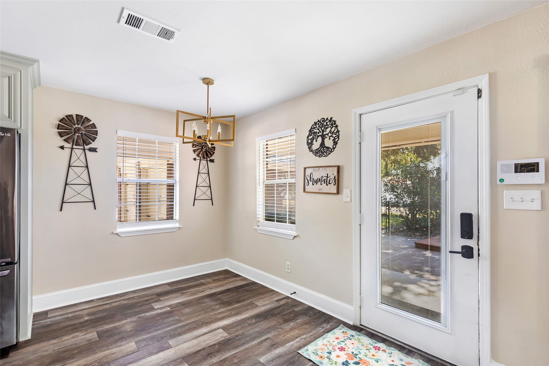 25107 Goodson Road, Splendora, TX 77372 Bright and inviting dining area with stylish wood-look flooring, modern light fixture, and decorative wall accents, leading to a patio through a glass door.