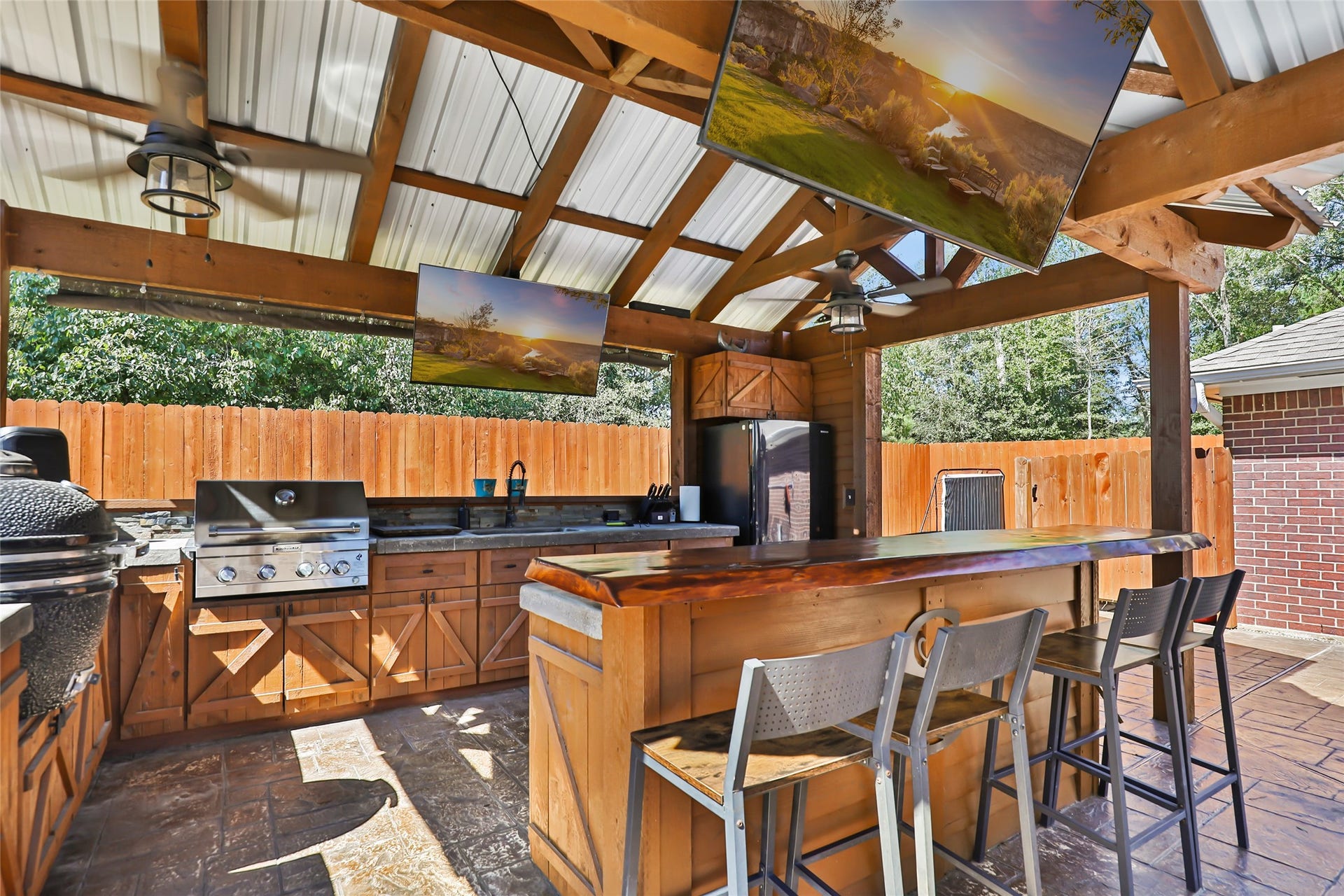25107 Goodson Road, Splendora, TX 77372 Outdoor kitchen oasis featuring a built-in grill, bar seating, and entertainment-ready space under a rustic pergola. Perfect for hosting gatherings.