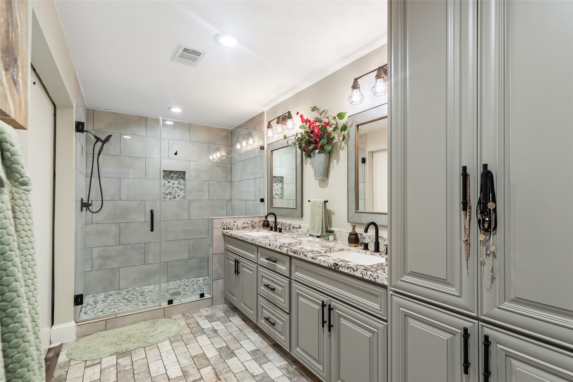 25107 Goodson Road, Splendora, TX 77372 Elegant bathroom featuring a spacious glass-enclosed shower, dual vanity with granite countertops, and ample cabinetry for storage.