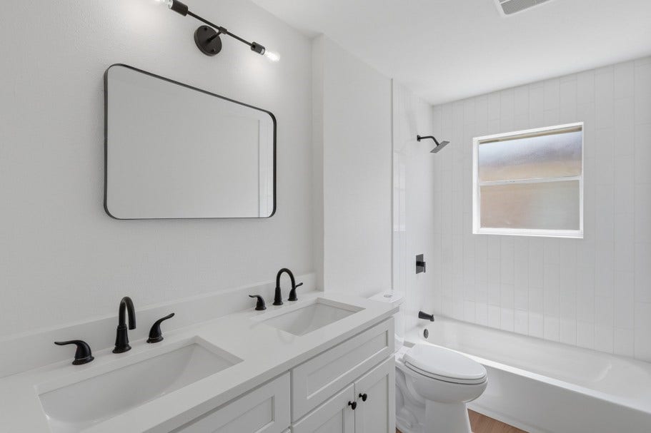 104 Oriole Lane, Angleton, TX 77515 The secondary bathroom features quartz countertops, dual sinks, and classic subway tile extending to the ceiling for a polished, timeless finish. The clean and simple design creates a bright, functional space with a modern touch.