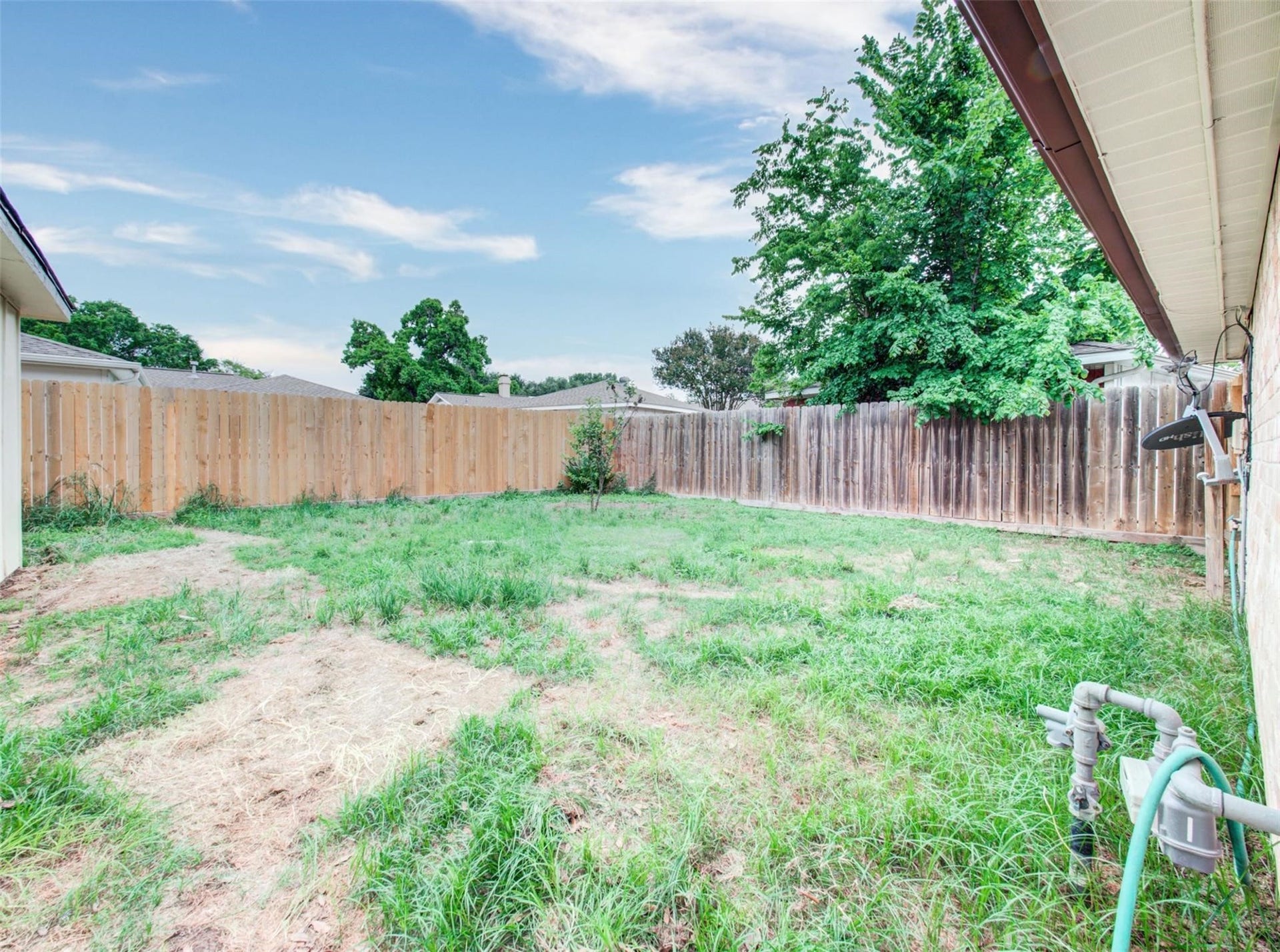 13526 Sherwood Street, Sugar Land, TX 77498 This backyard features a spacious grassy area enclosed by a wooden fence, offering privacy and potential for landscaping or outdoor activities.