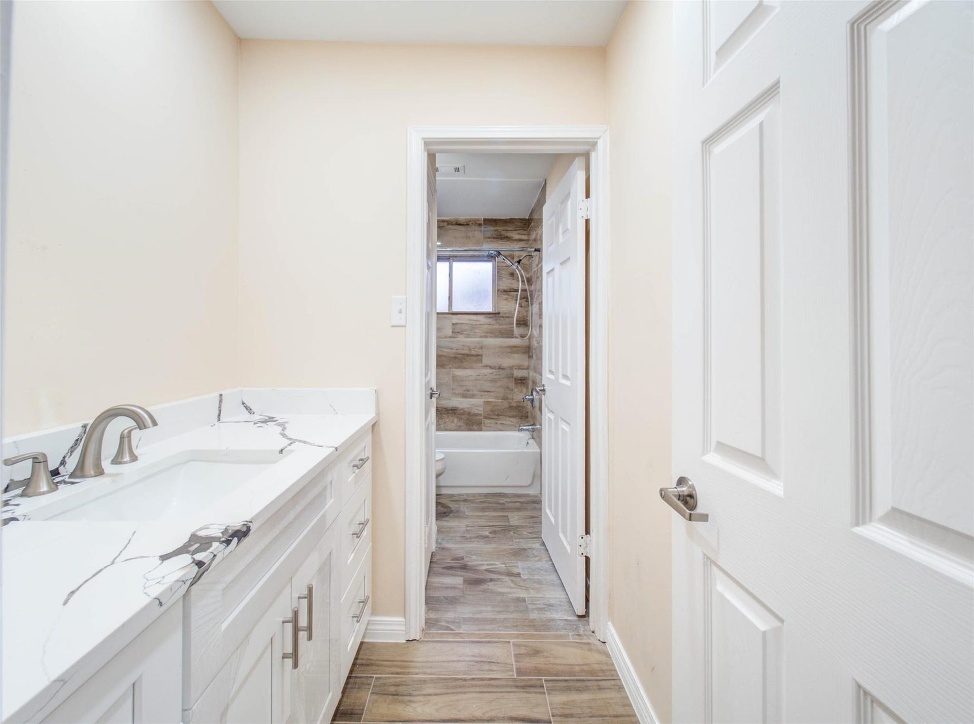 13526 Sherwood Street, Sugar Land, TX 77498 Bright and modern bathroom with a large granite countertop, dual sinks, and sleek fixtures. Features a tiled bathtub and shower, with wood-look flooring for a warm touch.