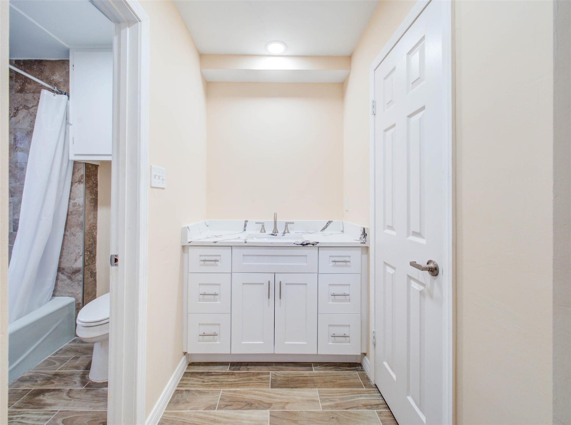 13526 Sherwood Street, Sugar Land, TX 77498 This bathroom features a modern vanity with ample storage, a sleek granite countertop, and a large mirror. It includes a bathtub with a shower curtain and elegant tile flooring, creating a clean and inviting space.