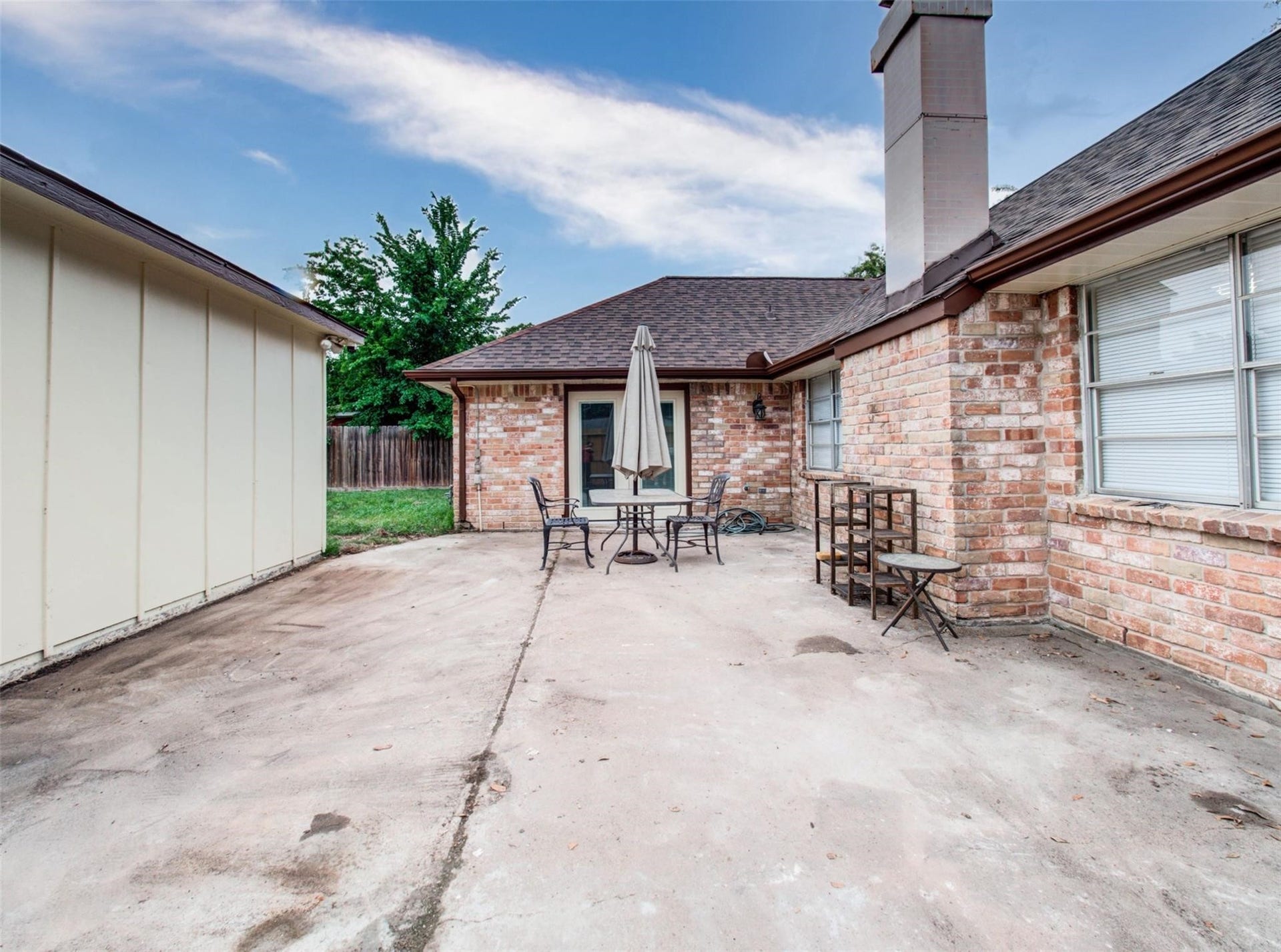 13526 Sherwood Street, Sugar Land, TX 77498 Spacious backyard patio with a concrete surface, brick exterior, and a cozy outdoor seating area. Ideal for gatherings, with a fenced yard providing privacy.