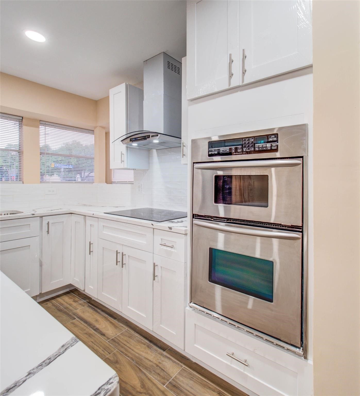 13526 Sherwood Street, Sugar Land, TX 77498 Modern kitchen with sleek stainless steel double ovens, white cabinetry, and wood-style flooring. Bright and inviting with ample natural light.