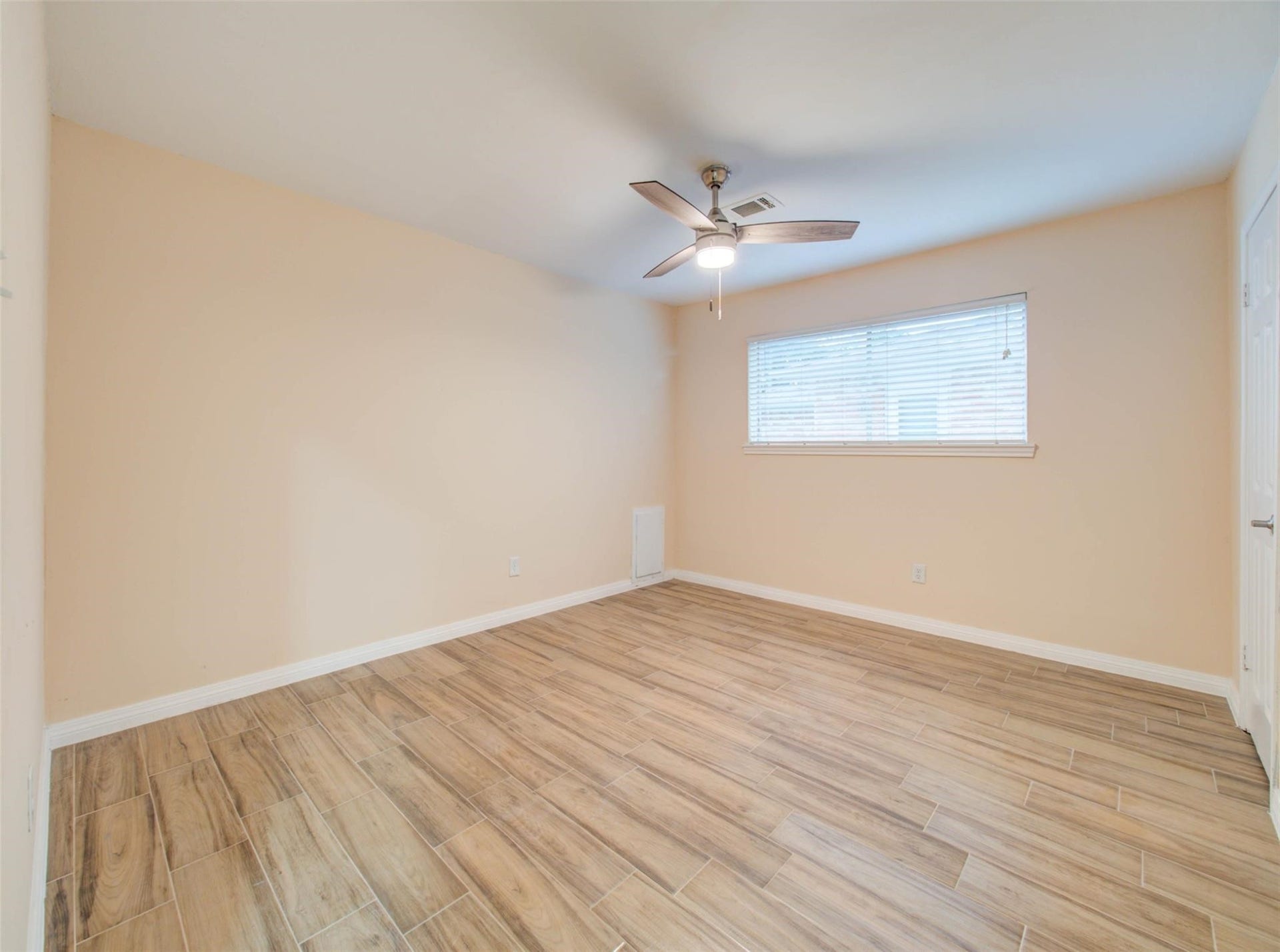 13526 Sherwood Street, Sugar Land, TX 77498 This is a bright, spacious room, neutral beige walls, a large window with blinds, and a ceiling fan, creating a comfortable and inviting atmosphere.