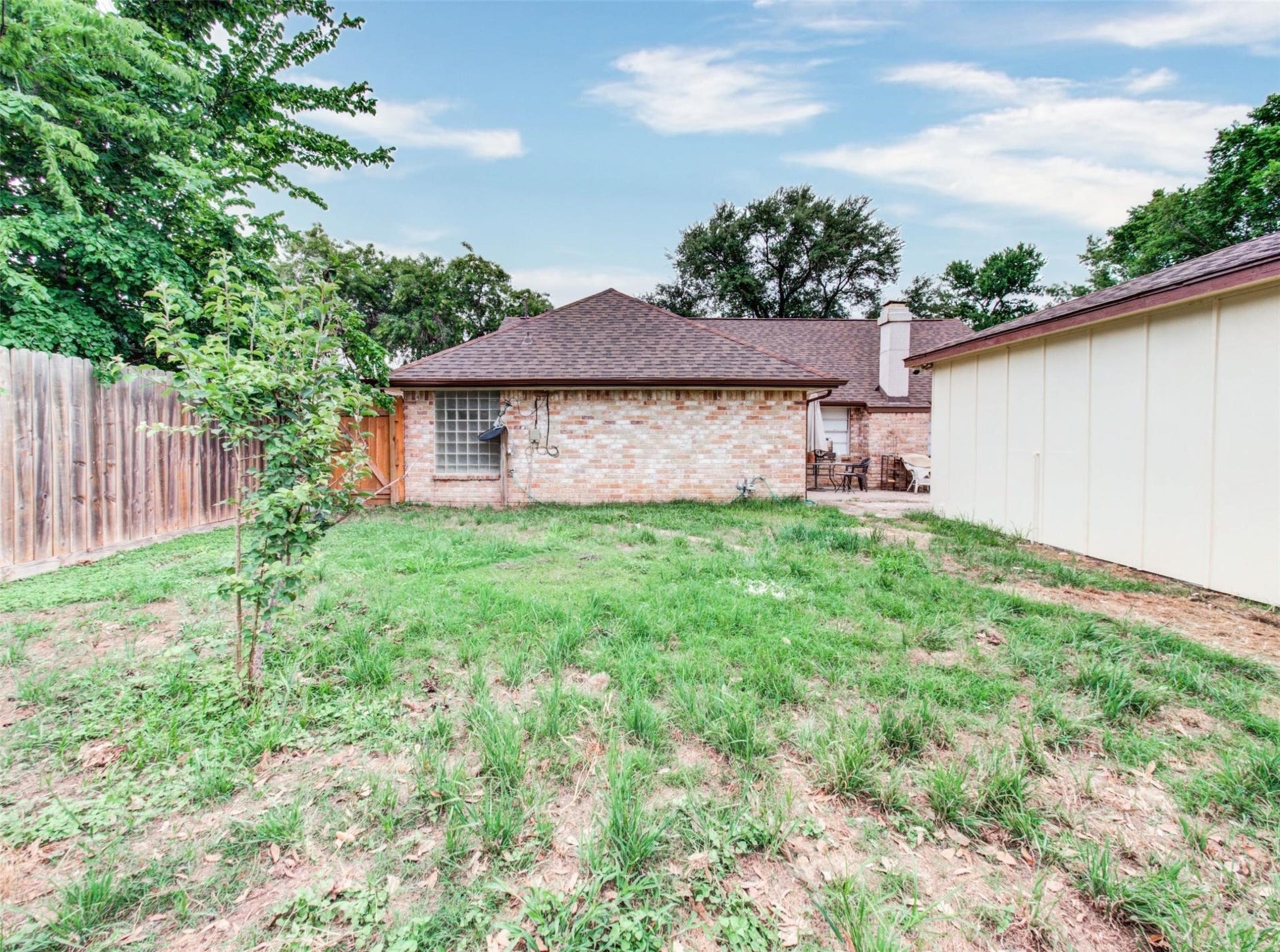 13526 Sherwood Street, Sugar Land, TX 77498 Spacious backyard with a brick house, wooden fencing, and a patio area, perfect for outdoor activities and entertaining.