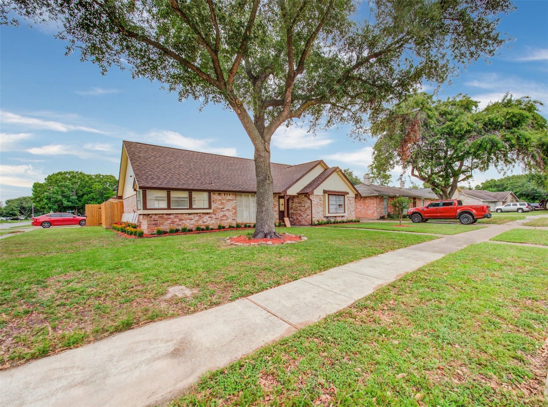 13526 Sherwood Street, Sugar Land, TX 77498 This charming single-story brick home features a gabled roof and manicured front yard with mature trees. It's located on a corner lot, offering ample outdoor space and a welcoming sidewalk entry.
