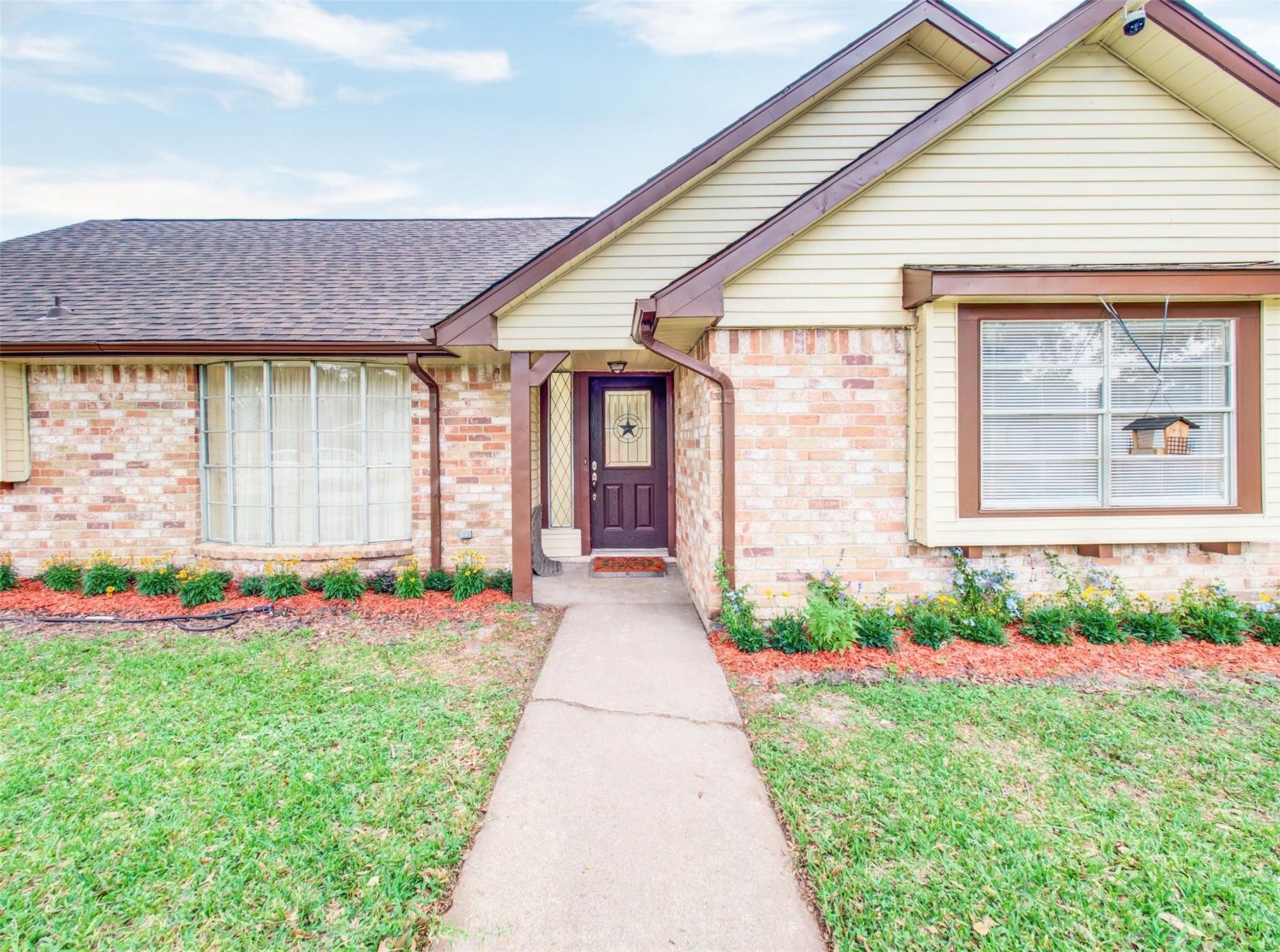 13526 Sherwood Street, Sugar Land, TX 77498 Charming single-story home with a welcoming entrance, featuring a neat pathway and well-maintained landscaping. The exterior boasts a combination of brick and siding, accented by a dark front door and large windows, allowing for plenty of natural light.
