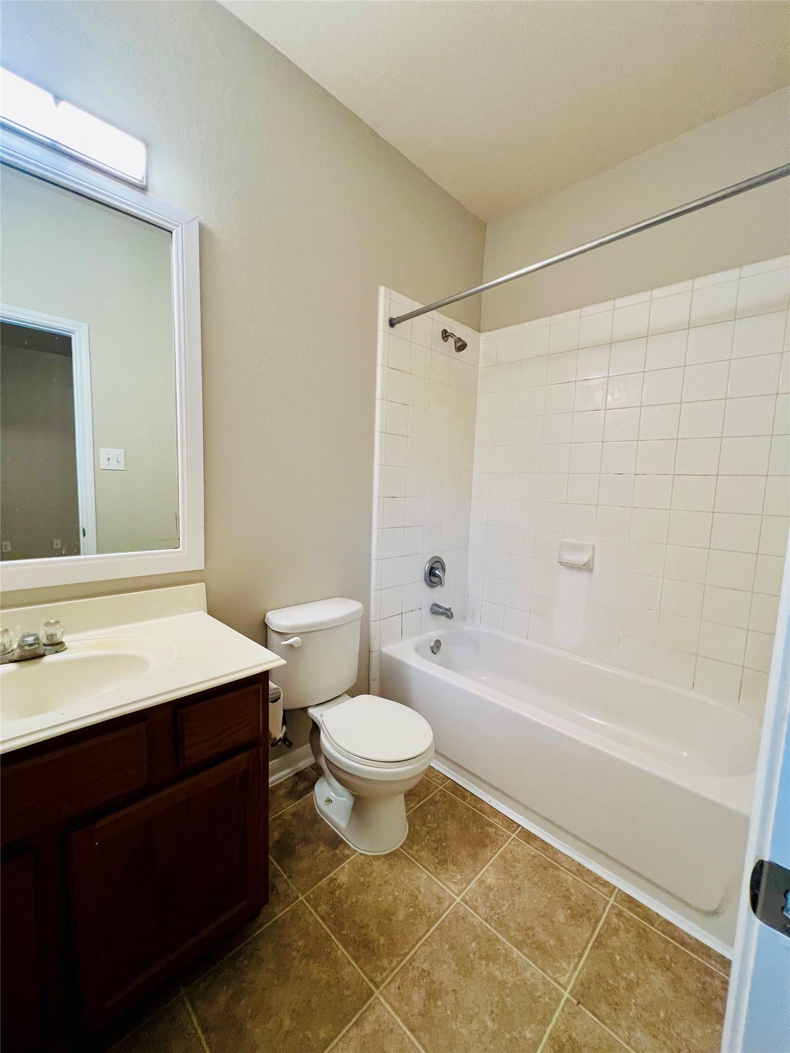 1721 Claremont Garden Circle, Houston, TX 77047 Bright and clean bathroom featuring a tiled shower-tub combination, a sleek vanity with ample storage, and neutral tile flooring.