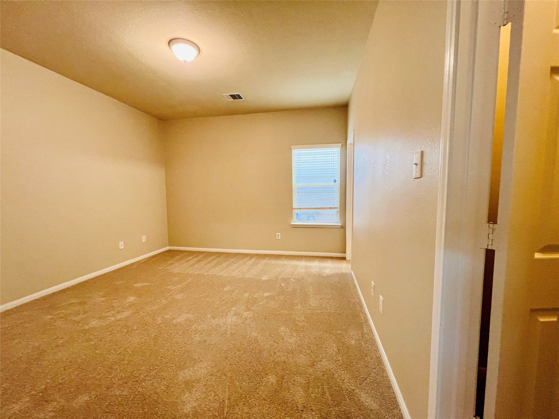 1721 Claremont Garden Circle, Houston, TX 77047 Spacious bedroom with soft carpeting, neutral walls, and ample natural light from a large window.