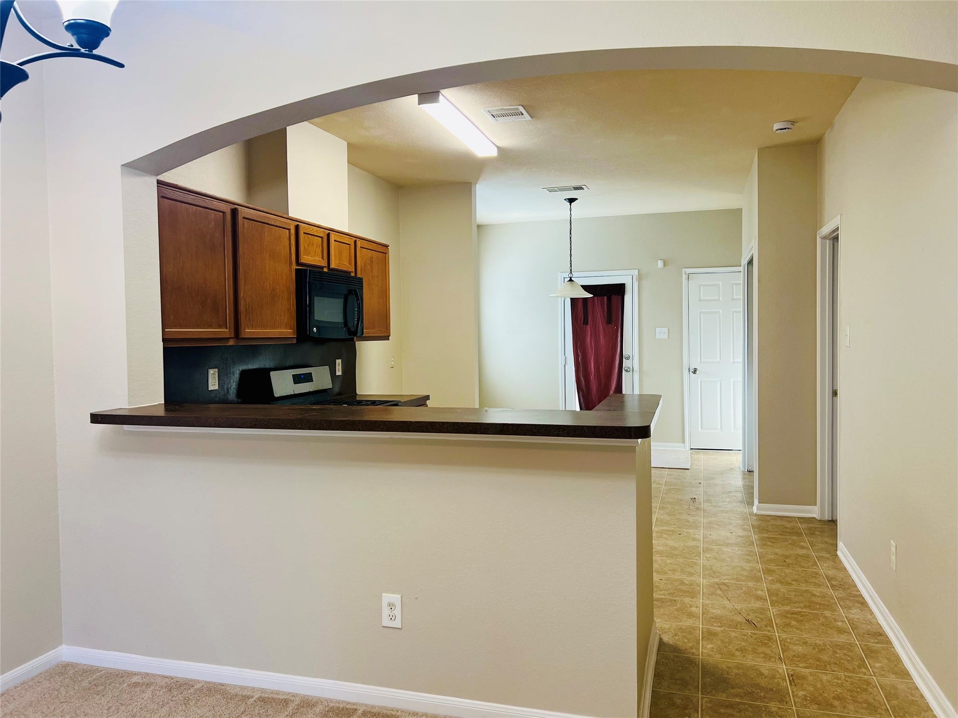 1721 Claremont Garden Circle, Houston, TX 77047 Charming open-concept kitchen with a convenient breakfast bar, featuring warm wood cabinetry, modern appliances, and a cozy adjoining dining area with tile flooring.